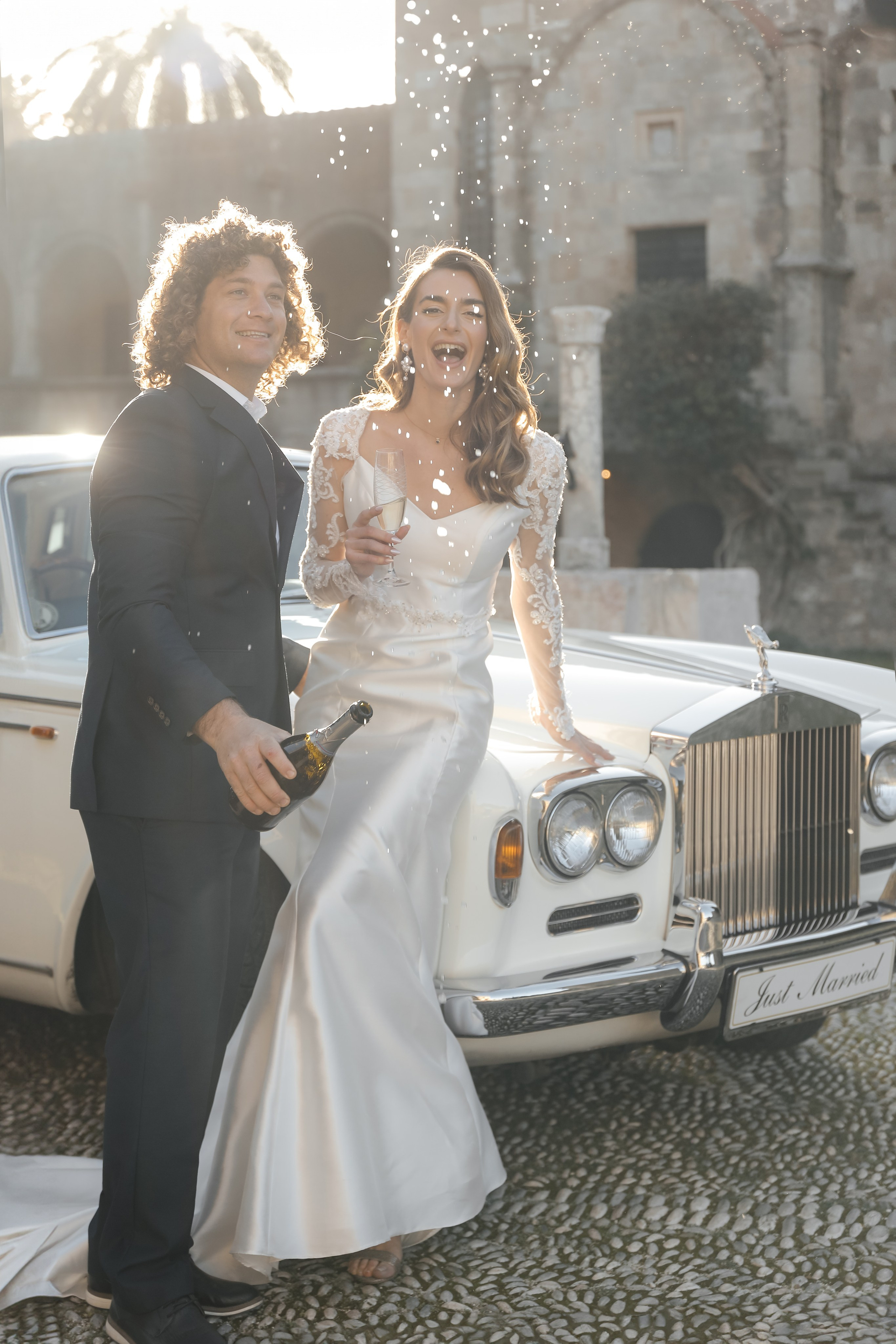 A bride and groom next to Rolls Royce in old town of Rhodes island, Greece