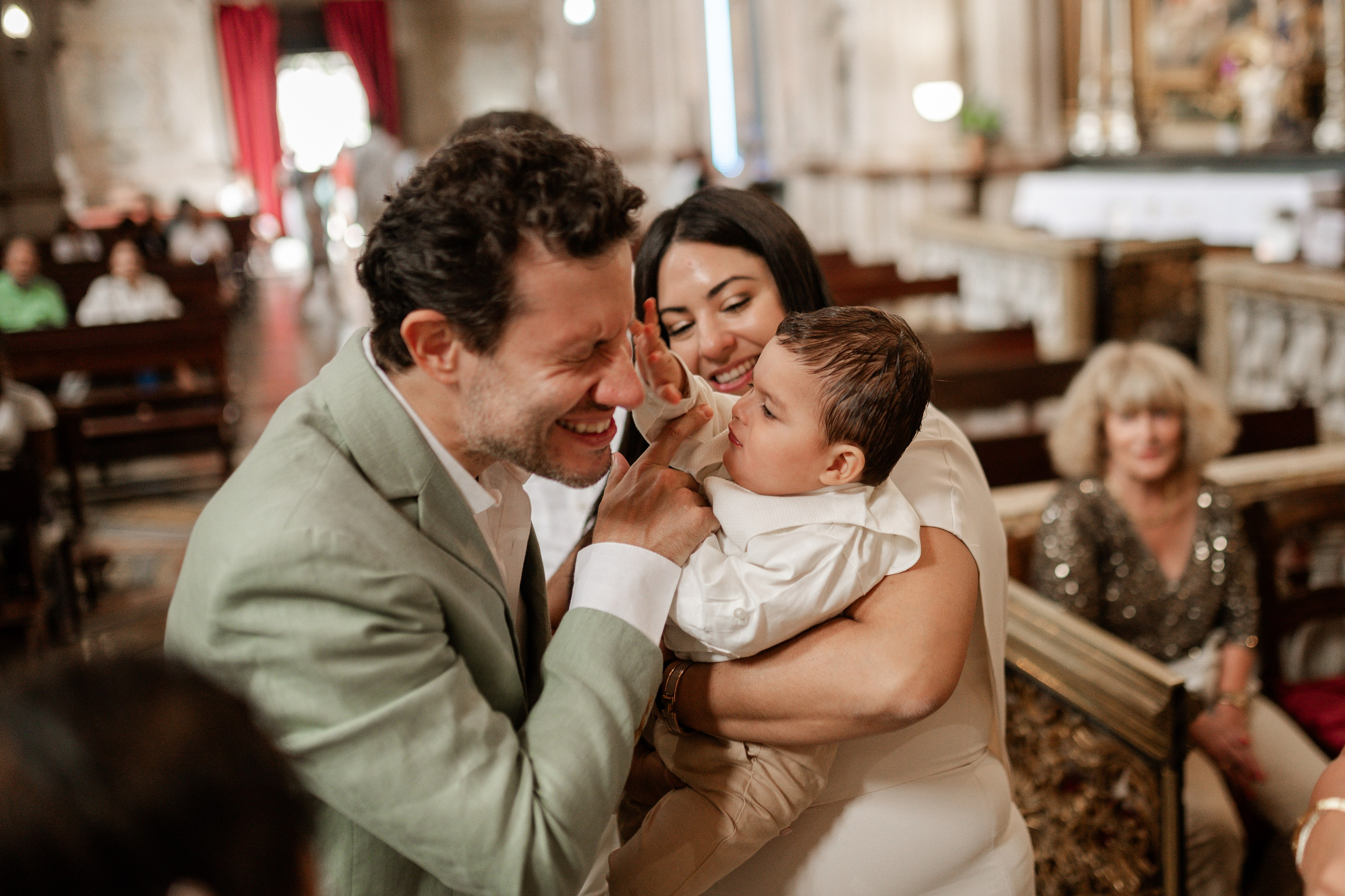 Церемония крещения в церкви, семья вокруг младенца во время обряда, тёплый и эмоциональный момент