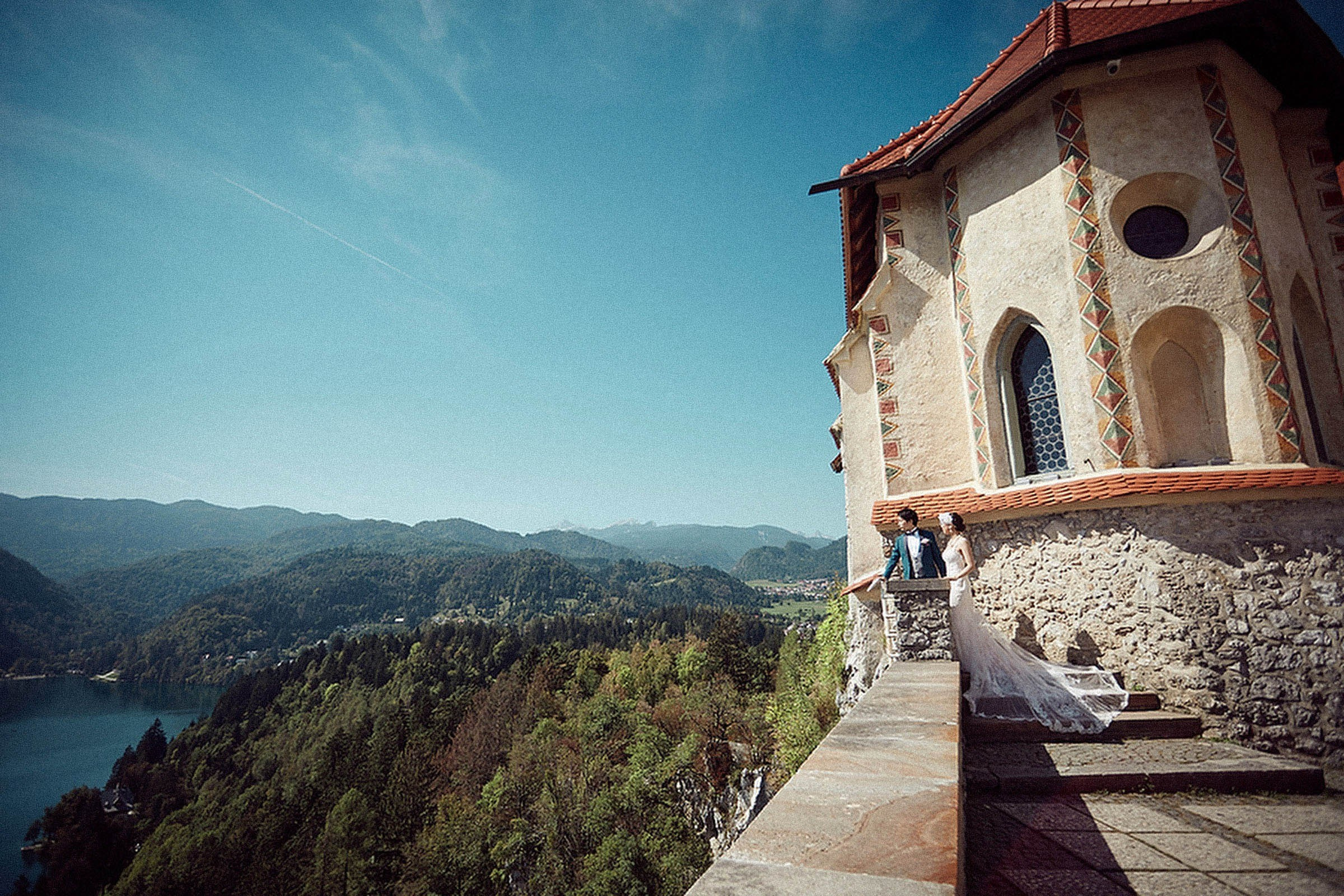Couple gazing over Lake Bled panoramic view from Bled Castle terrace.