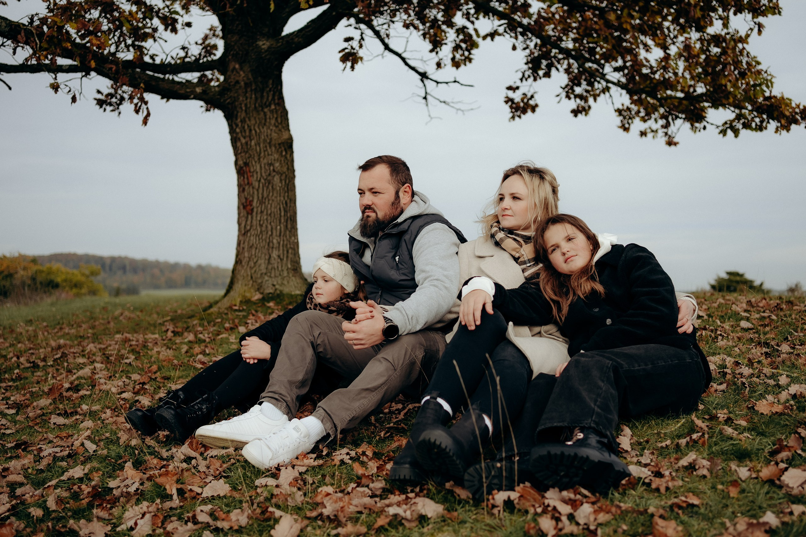 Mehrere Familienmitglieder sitzen entspannt unter einem Baum.