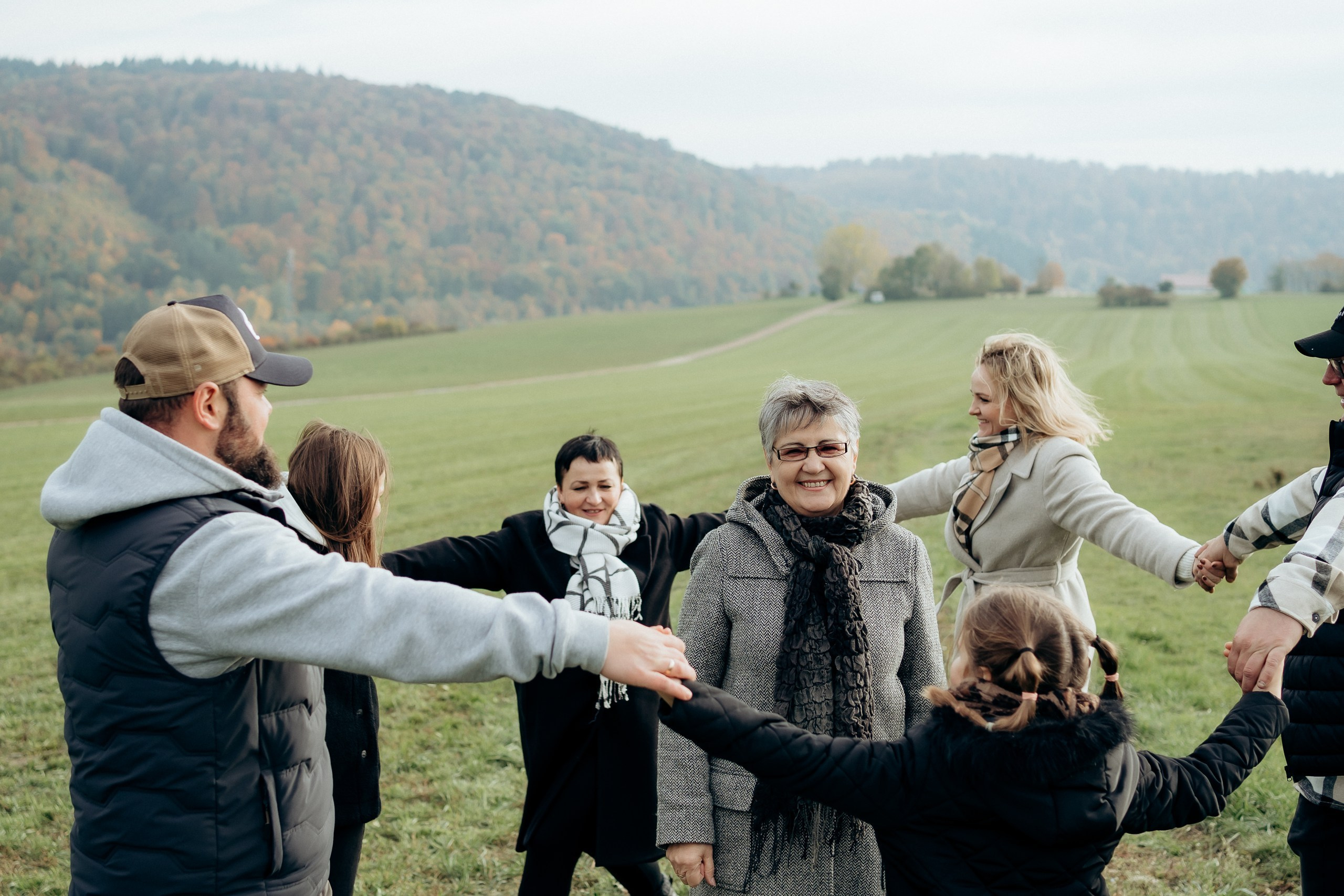Familienmitglieder halten sich an den Händen und bewegen sich gemeinsam über eine Wiese.