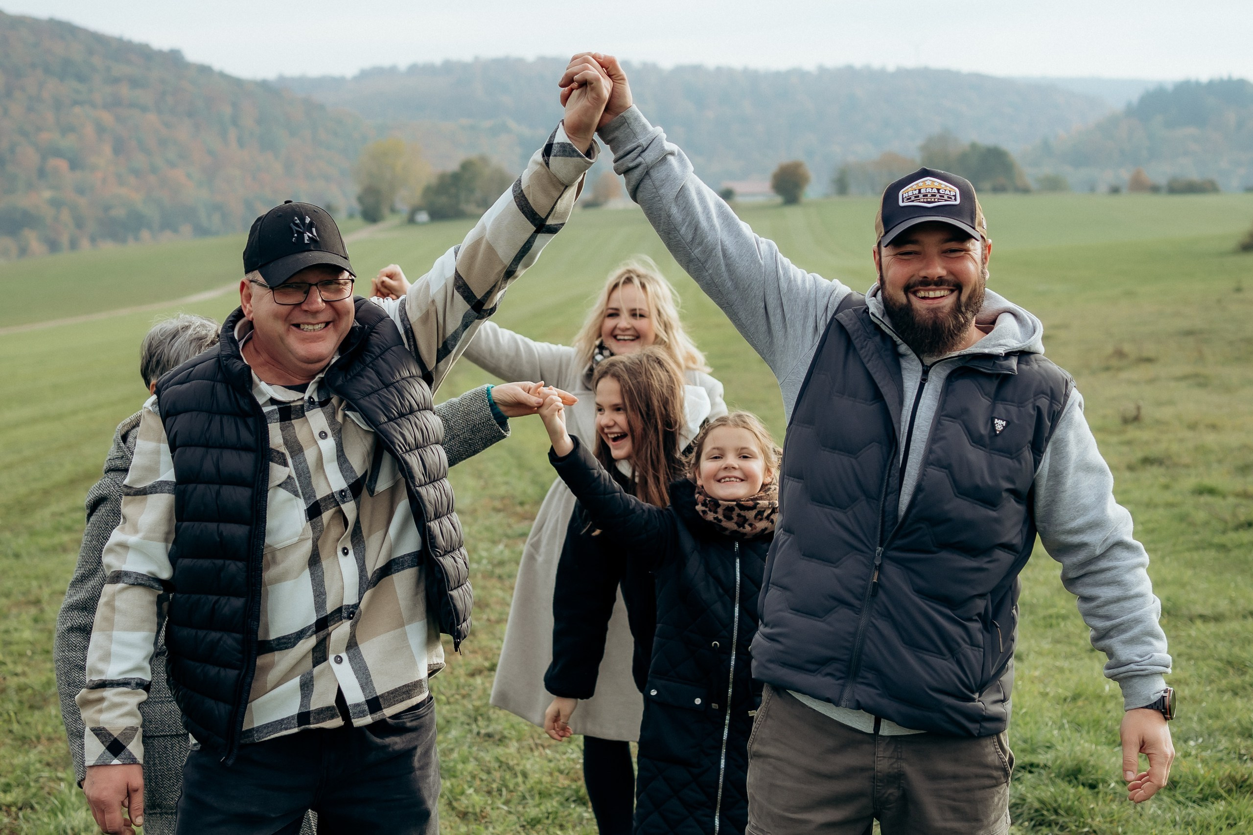 Drei Familienmitglieder lachen und heben gemeinsam ihre Arme.