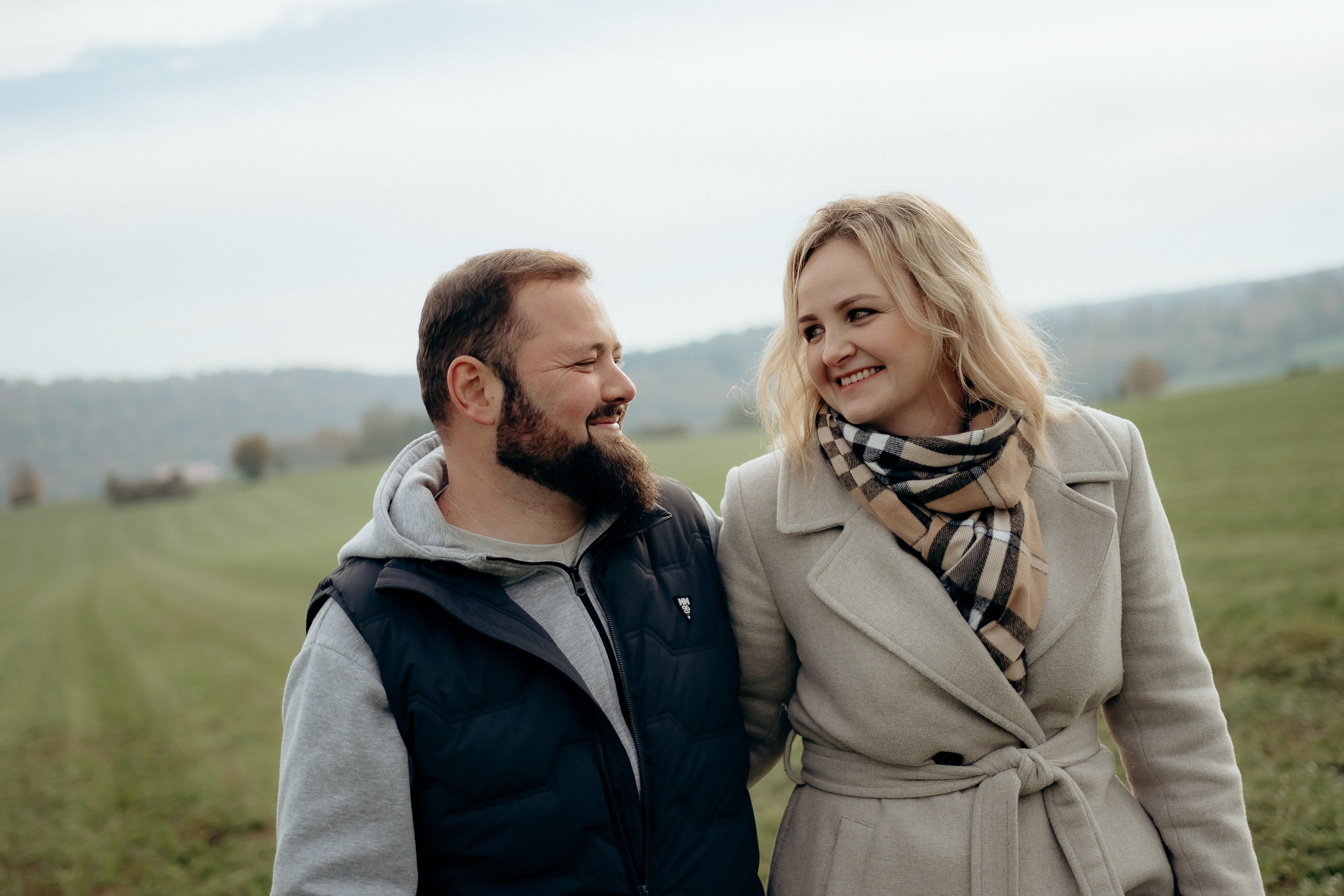 Zwei Familienmitglieder gehen Hand in Hand über eine grüne Wiese.