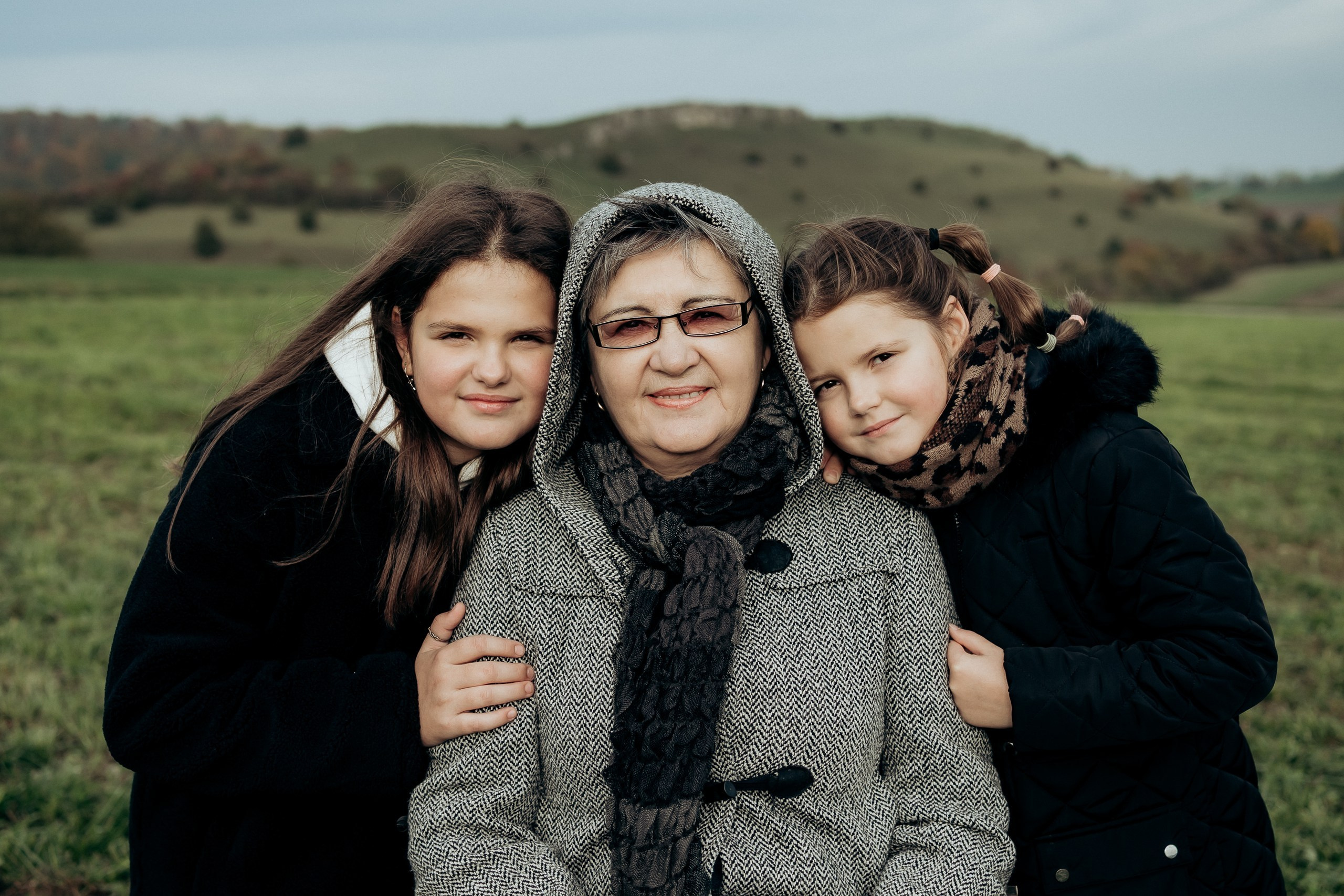 Drei Frauen verschiedener Generationen stehen eng beieinander und lächeln.