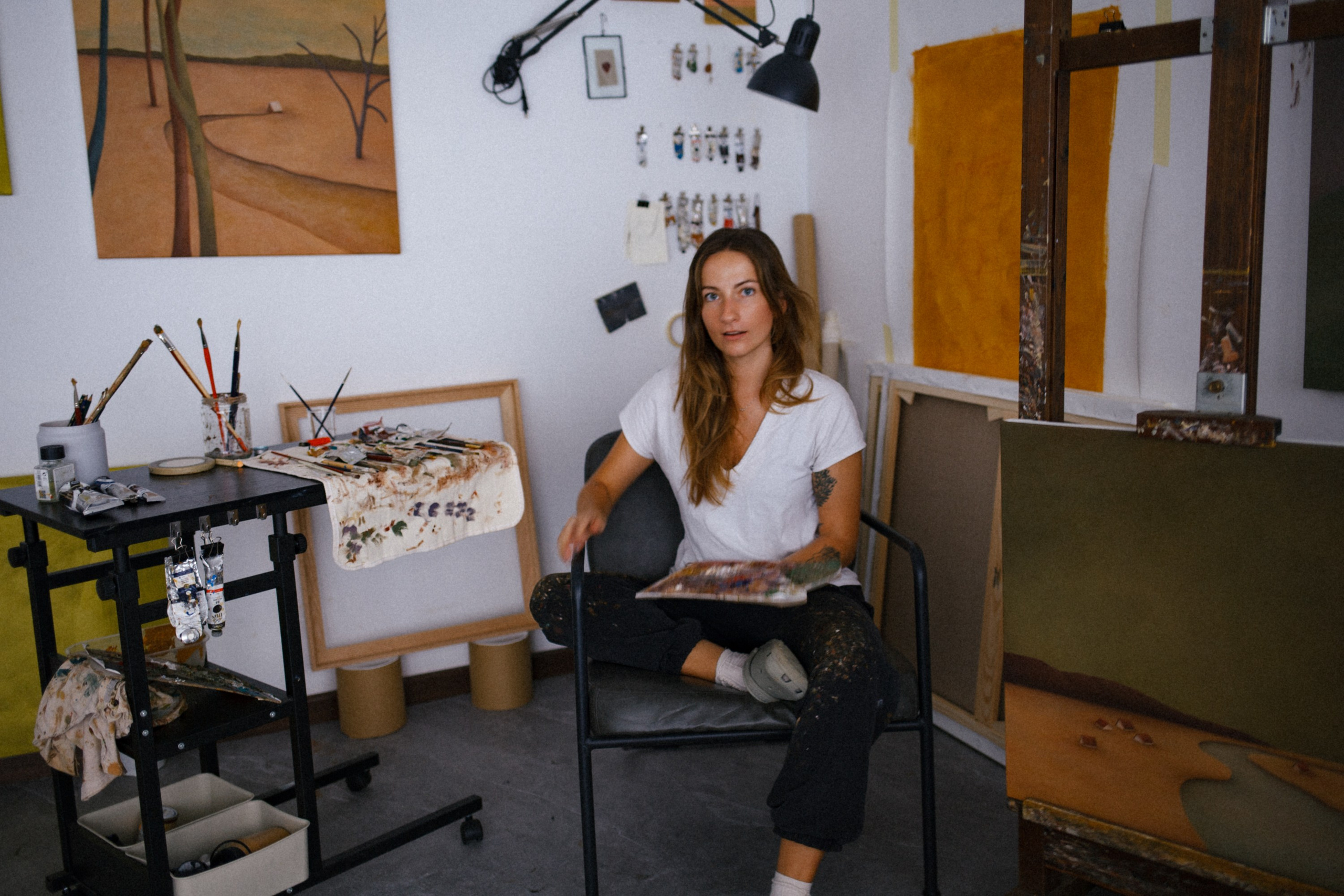 Zuzana Rohelová sitting in her studio surrounded by canvases