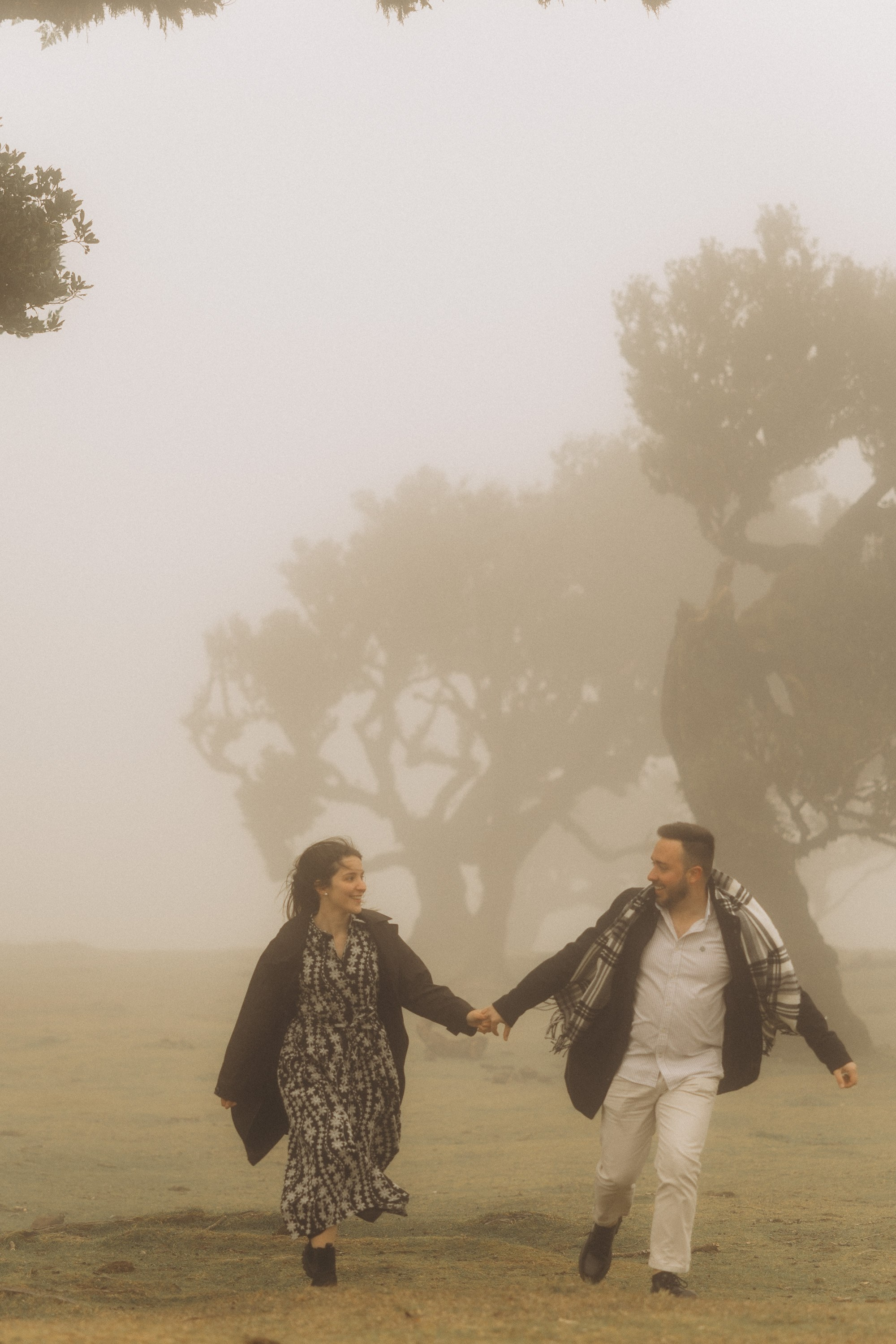 Couple photoshoot in Fanal Forest Madeira PortugalA romantic couple standing amidst the ancient laurel trees of Fanal Forest, Madeira, surrounded by a mystical fog that adds an ethereal touch to the scene