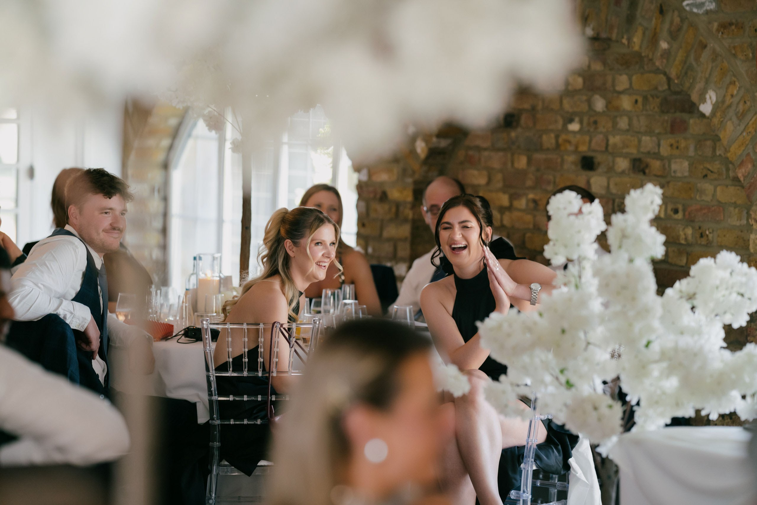 Elegant UK wedding reception with guests laughing during speeches, candid emotional moments captured by London wedding photographer, natural storytelling wedding photography
