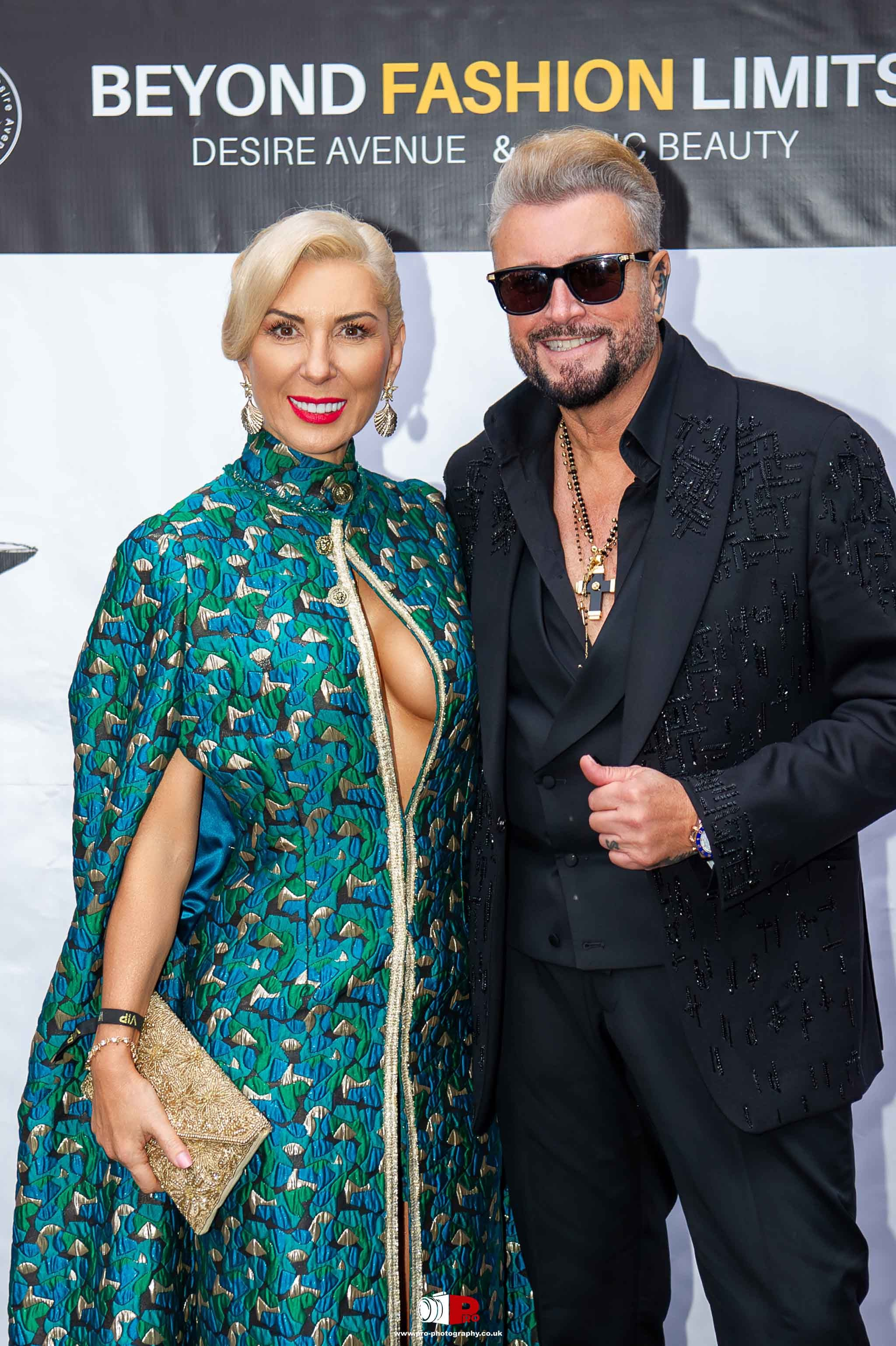 A glamorous couple posing on the red carpet at the Beyond Fashion Limits charity event, dressed in luxury fashion attire.