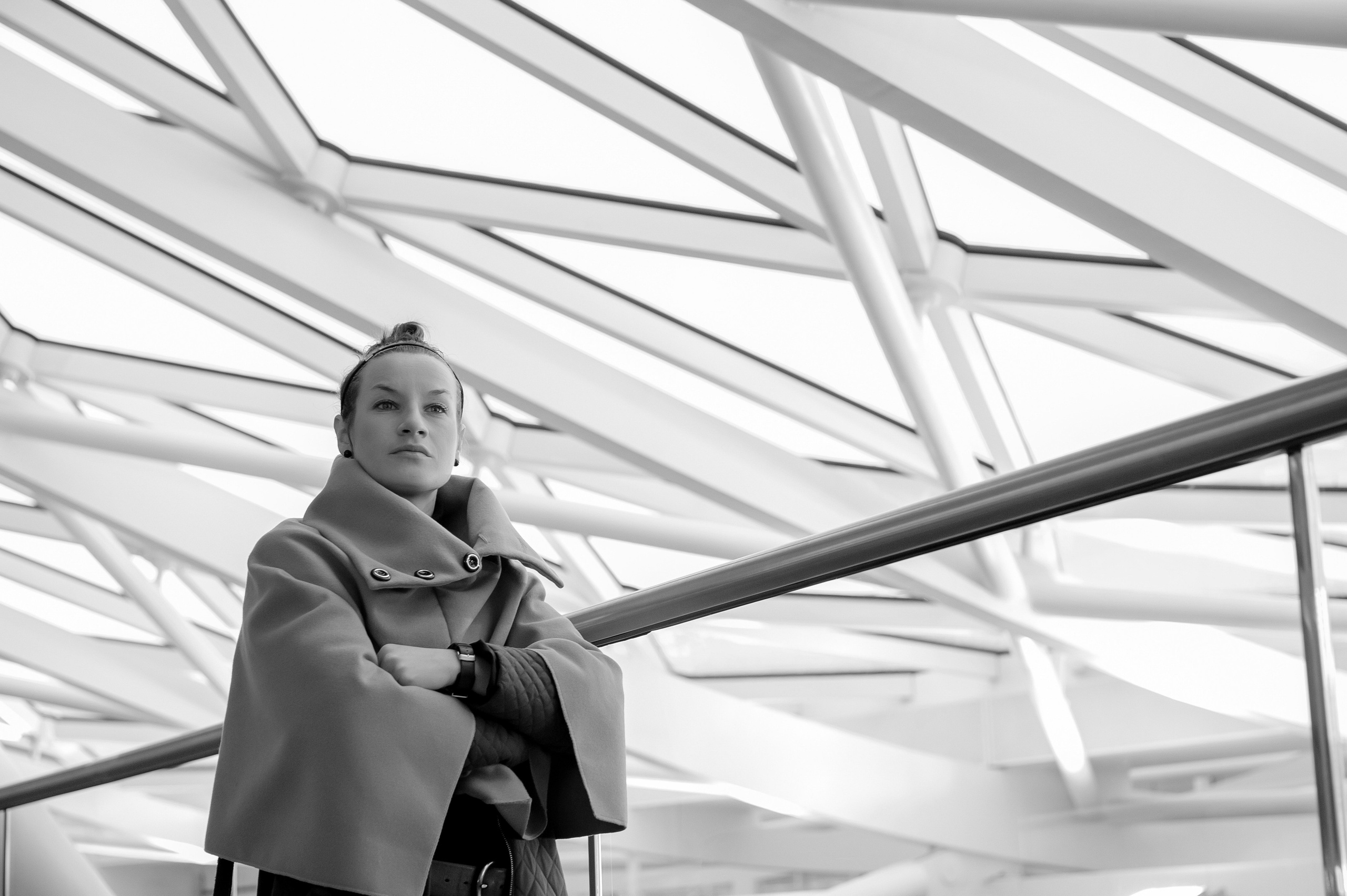 Portrait of a woman in black and white style against the background of the glass roof of King's Cross station.