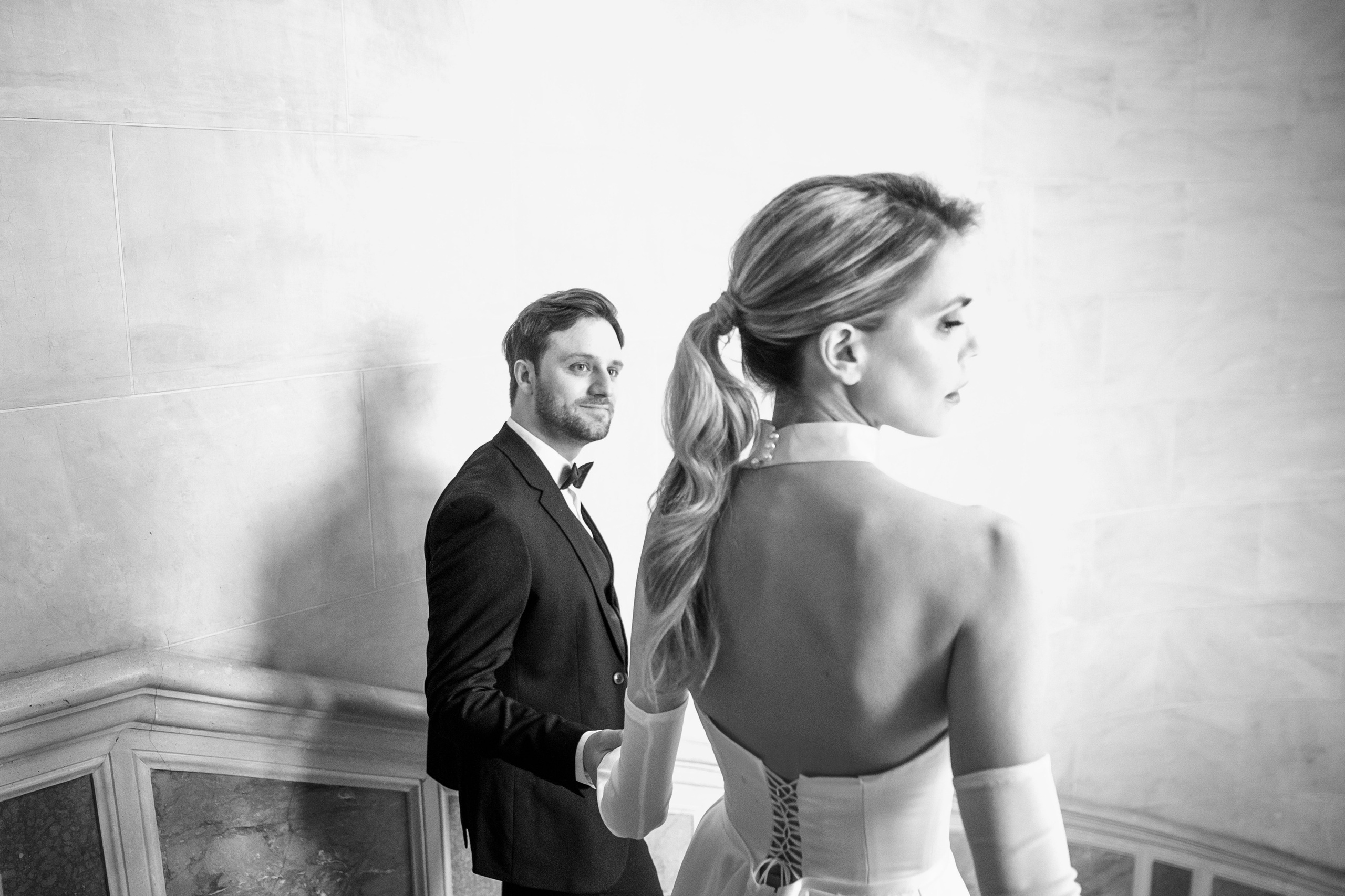 The bride and groom walk hand in hand down the stairs in a beautiful French chateau. 