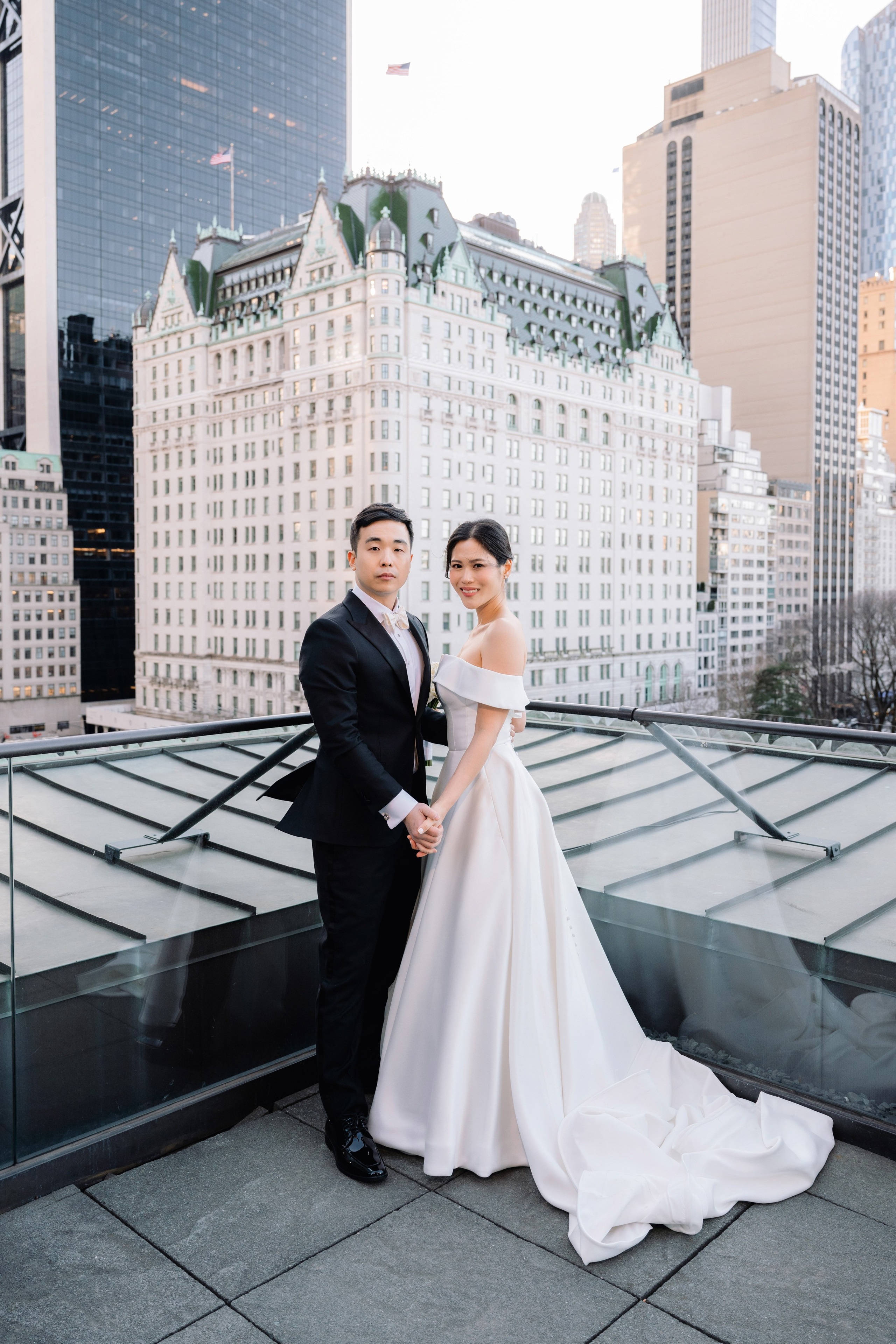 a bride and groom pose for a photo on the rooftop of the hotel