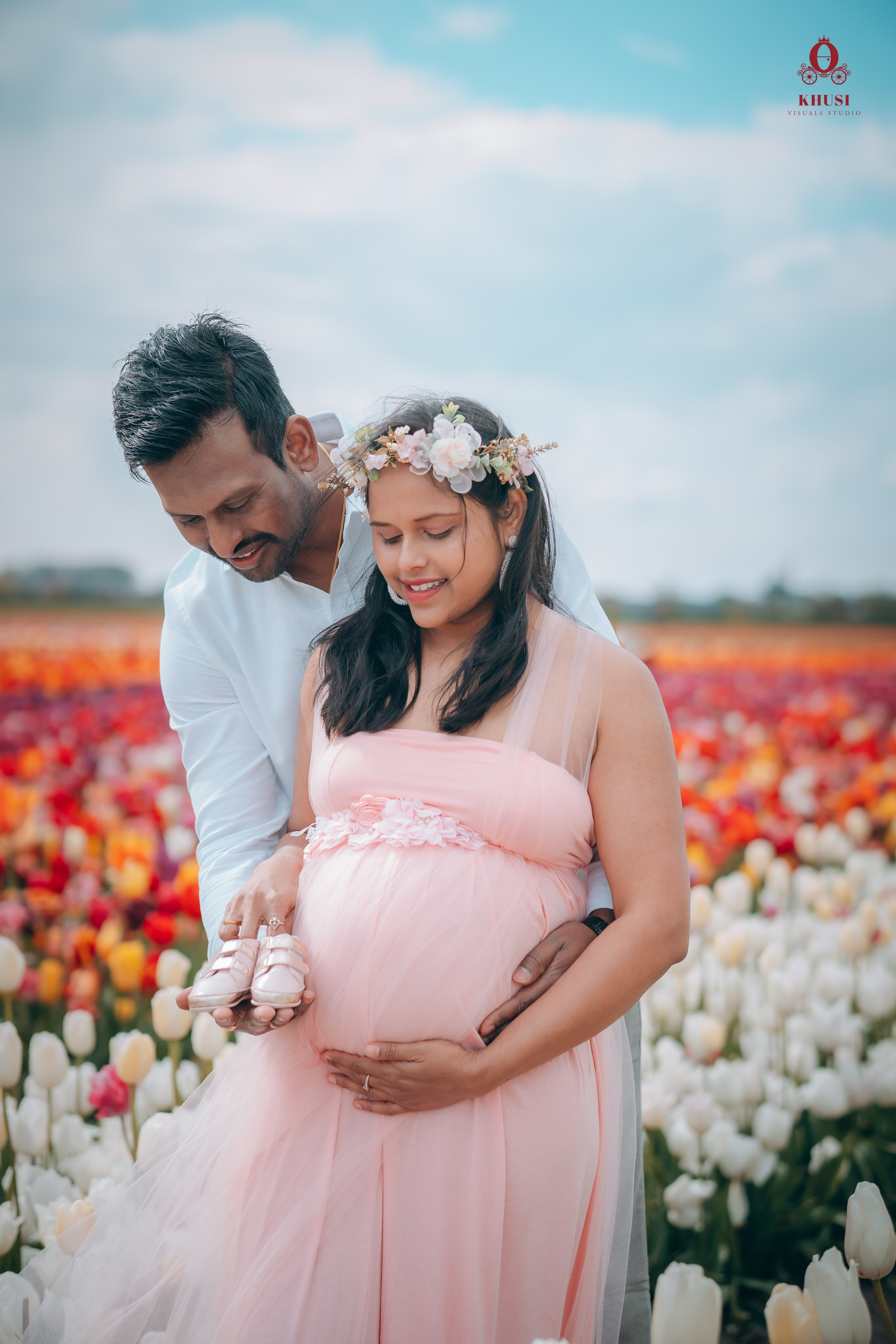 A couple holding baby sneakers in a tulip fields of netherlands