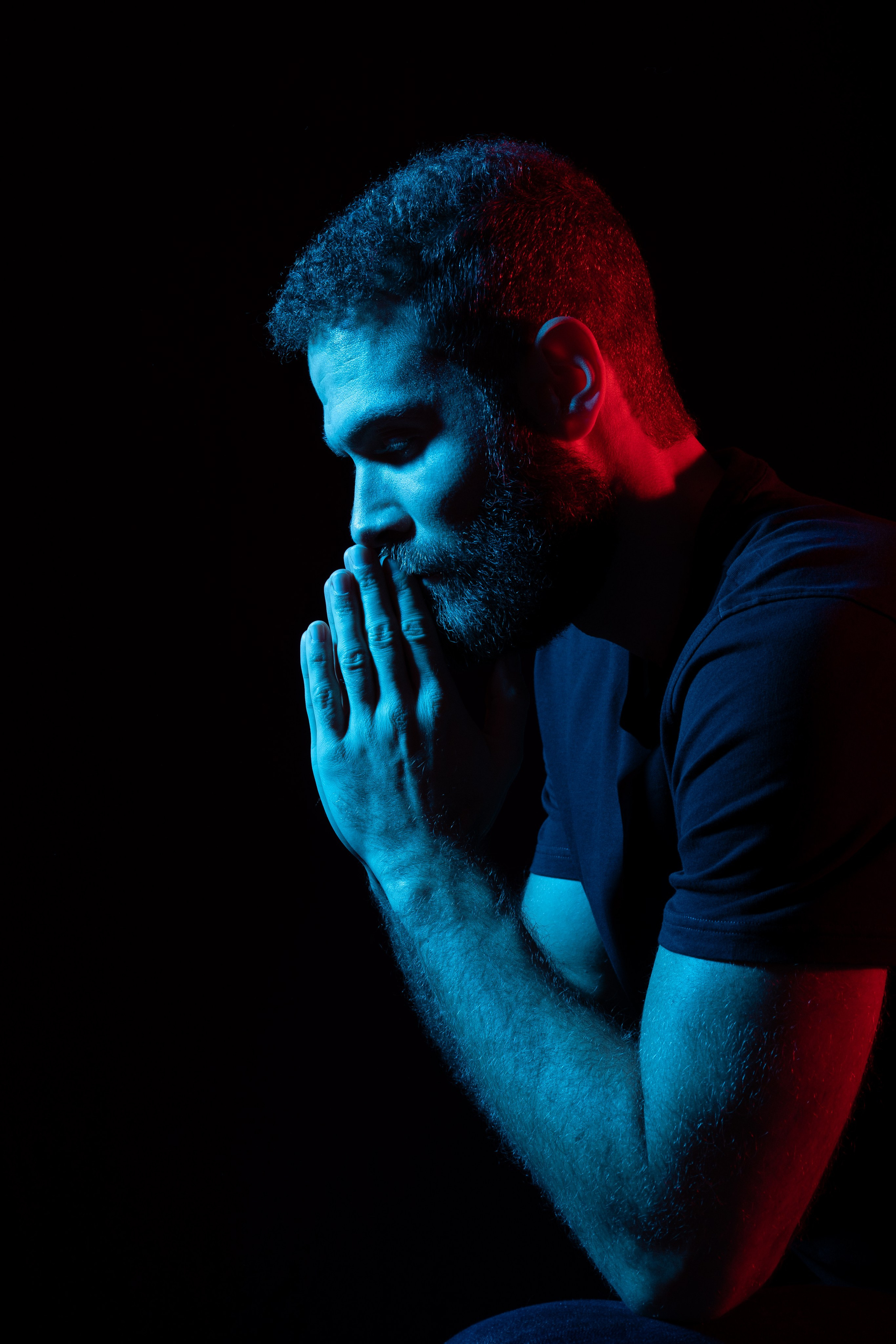 Dunkles Low-Key-Männerporträt mit farbigem Licht im Studio