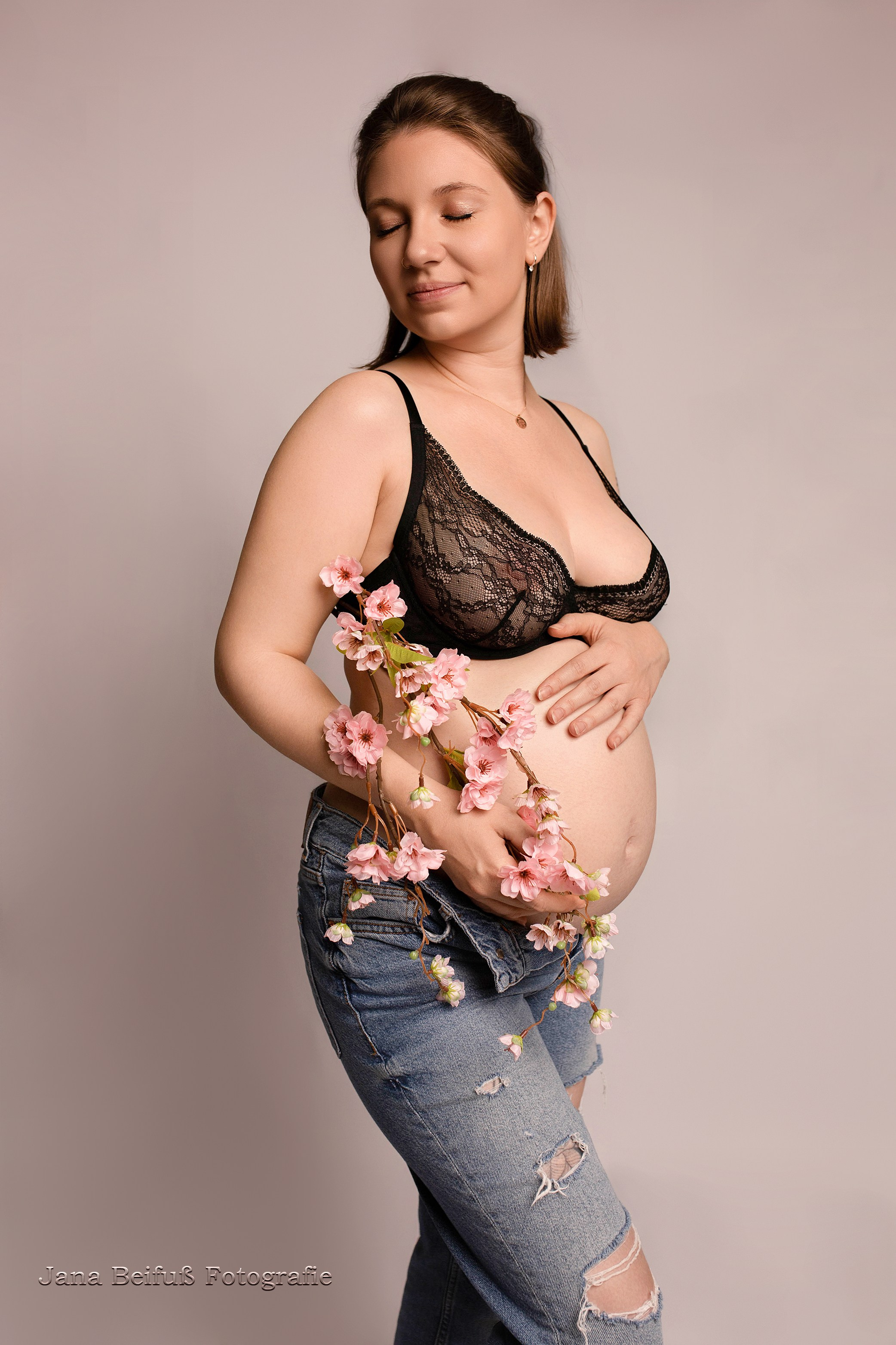 Werdende Mama in Spitzenunterwäsche und Jeans und Blumen und geschlossenen Augen - Schwangerschaftsfotografin Weißenhorn bei Ulm