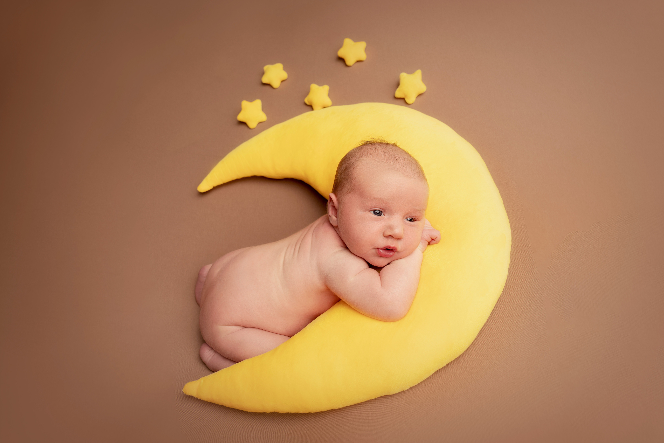 Ein neugeborener Junge liegt auf einem kuscheligen Mond 