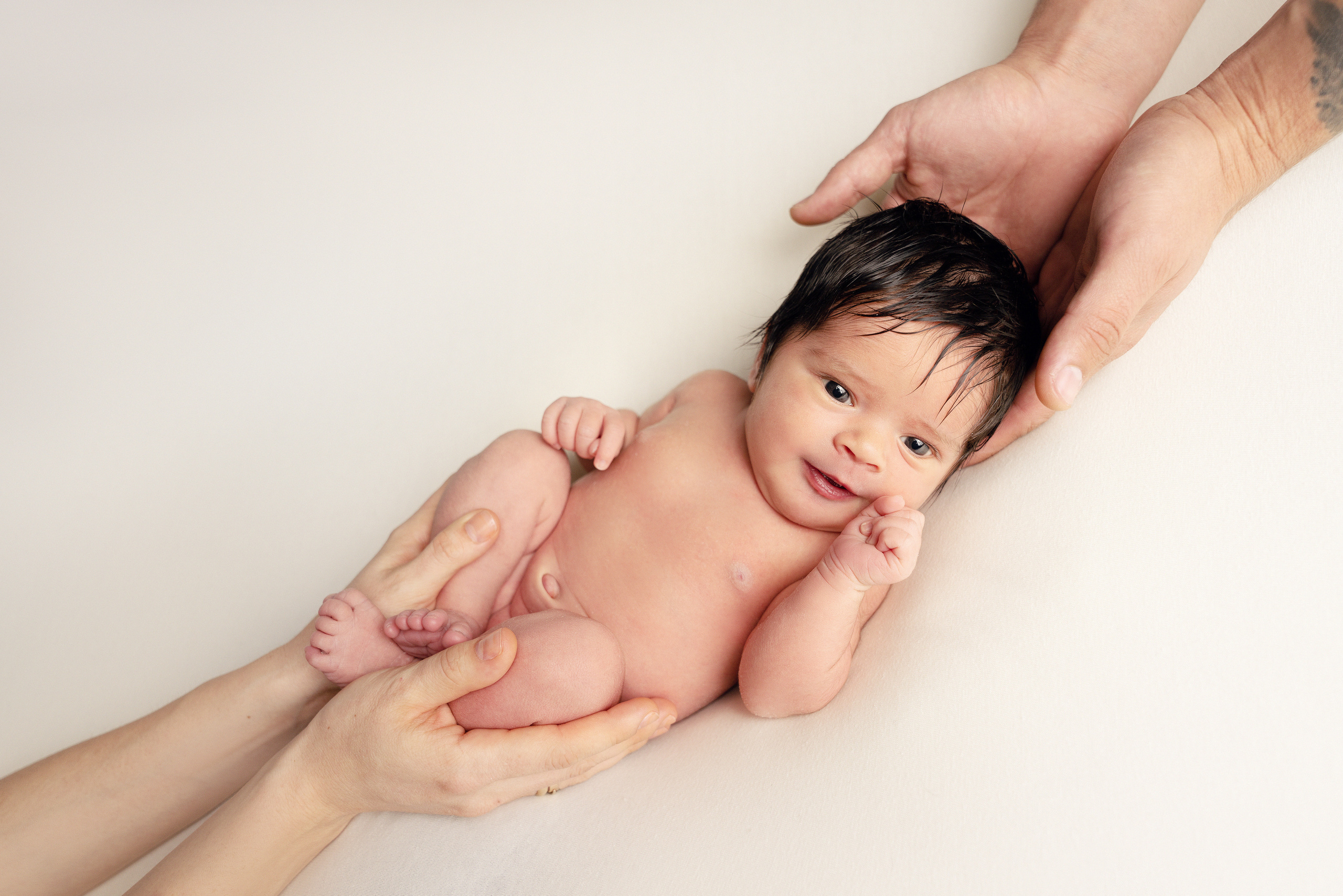 Ein Baby liegt in den Armen von Eltern