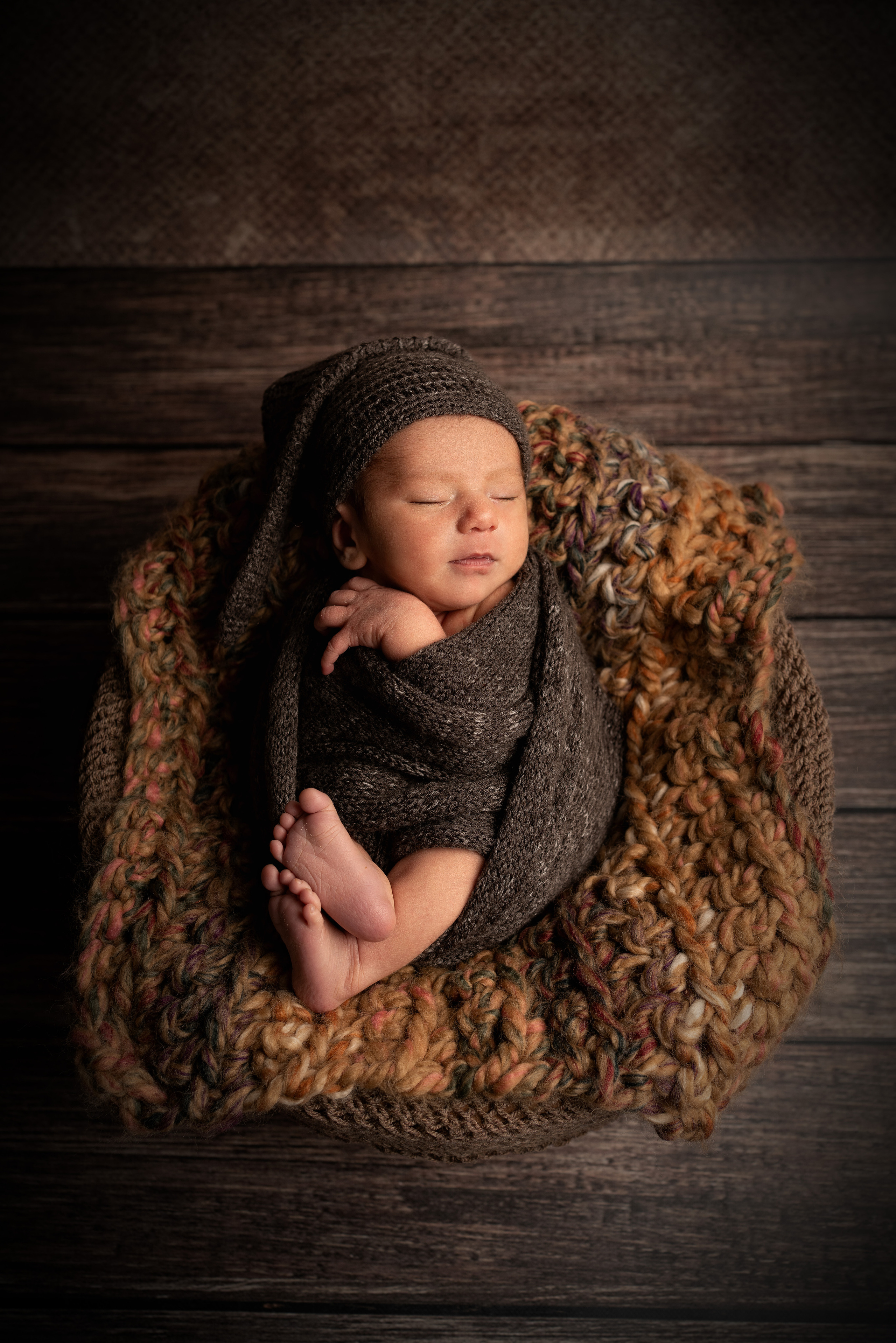Ein neugeborener Junge schläft auf einem brauen Tuch.