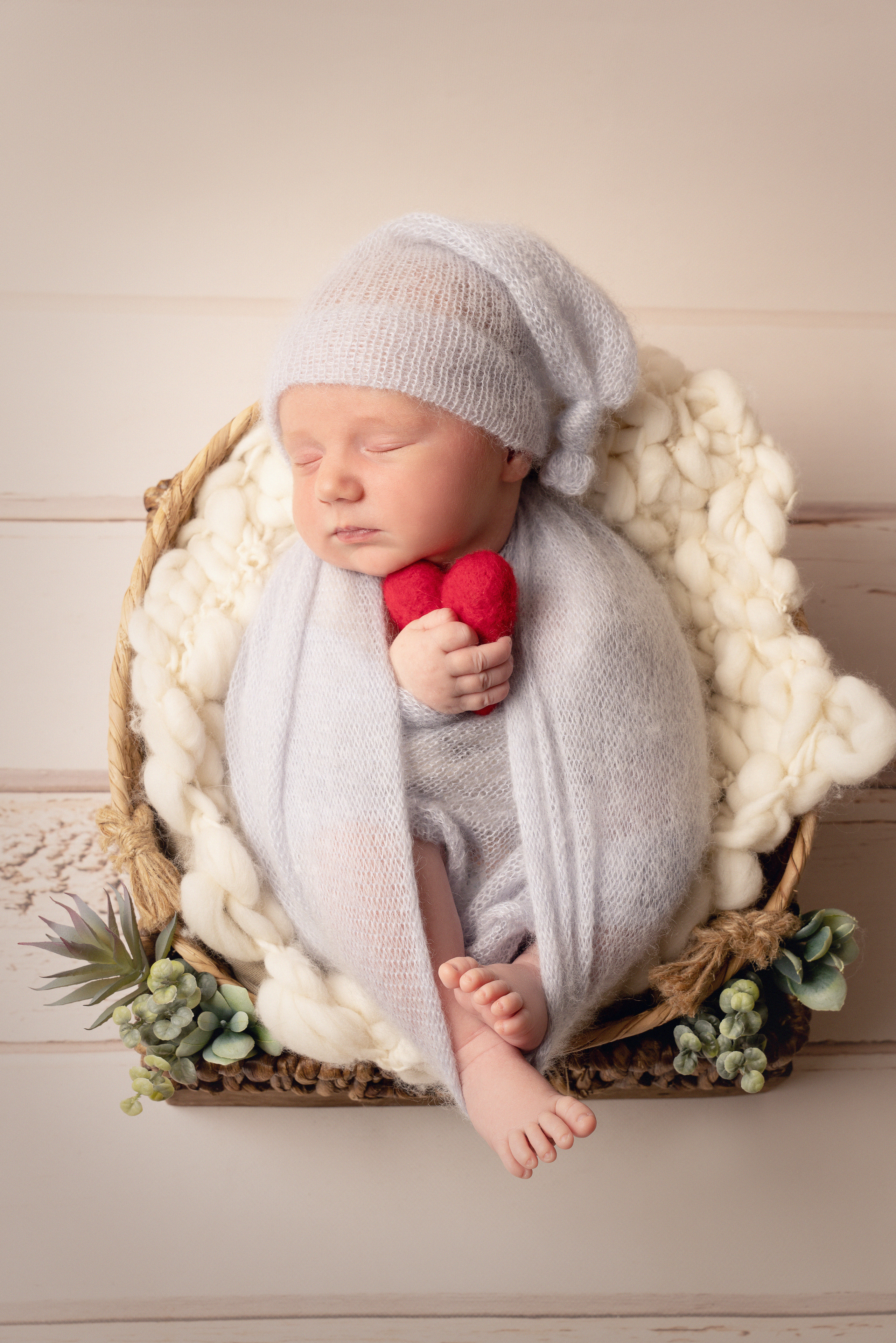 Ein Baby hält einen Herzhen in seinen Arm.