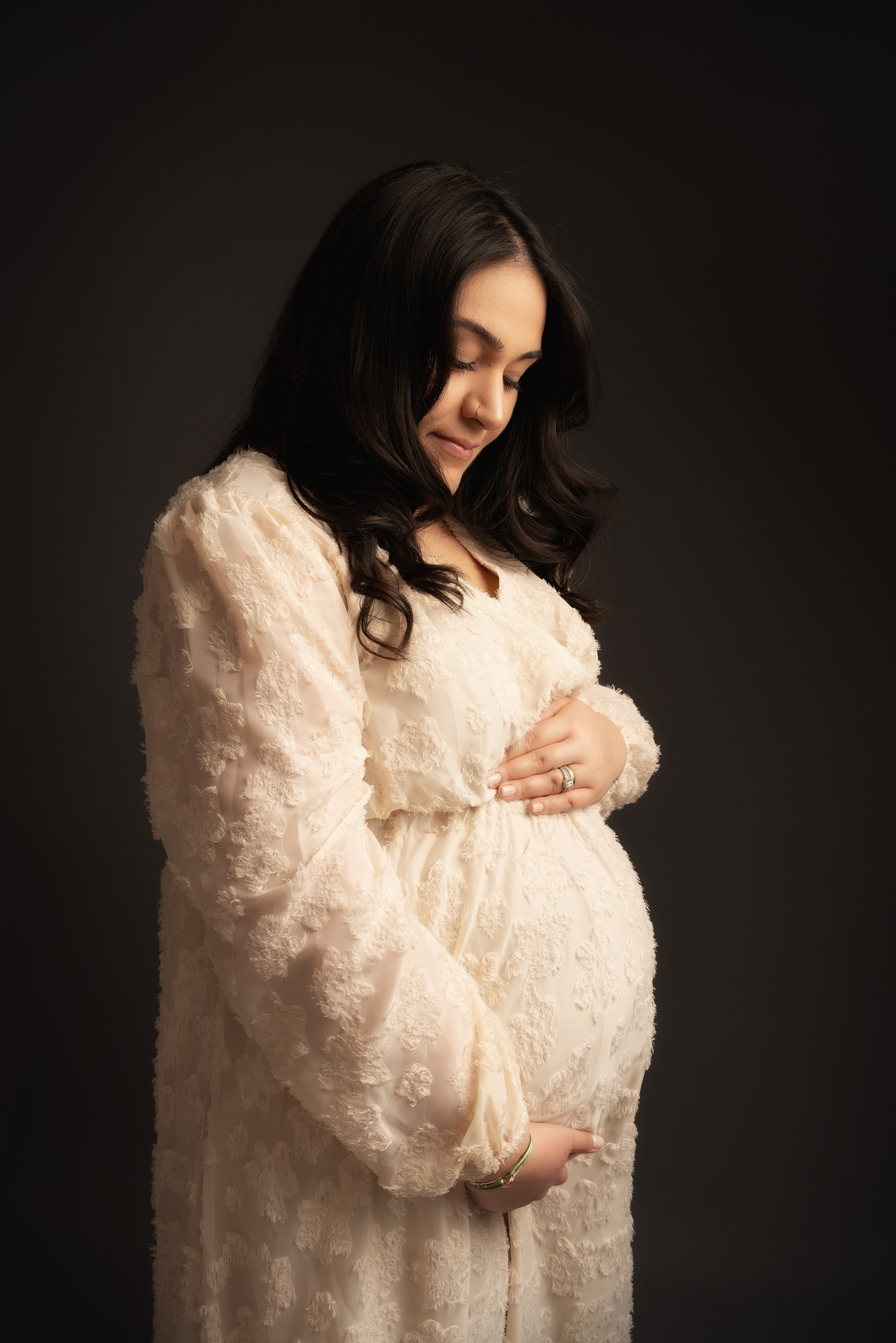 Eine schwangere Frau hält liebevoll ihren Bauch und lächelt