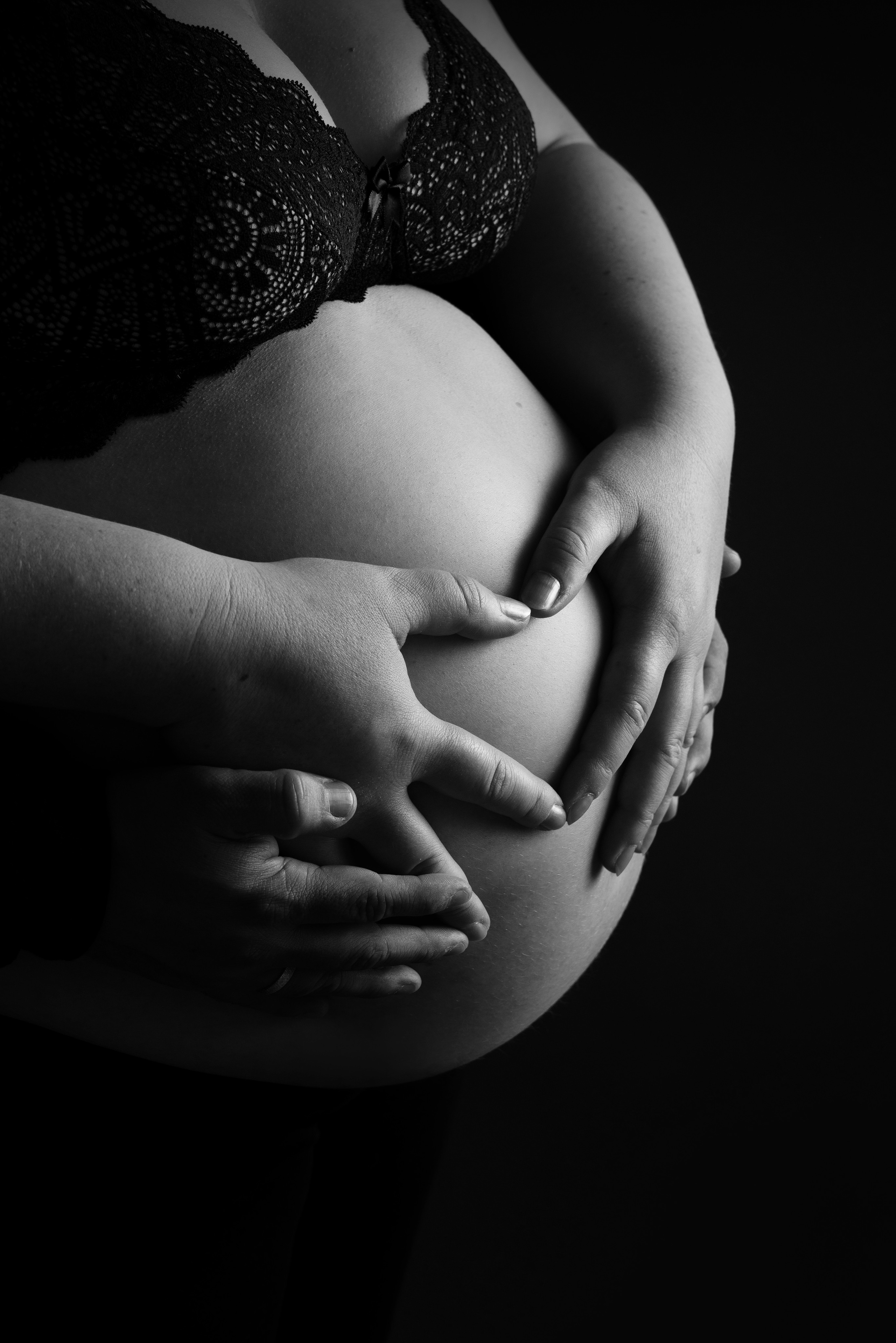 Eine Frau mit babybauch posiert mit Kleidung für ihr zukünftiges Baby