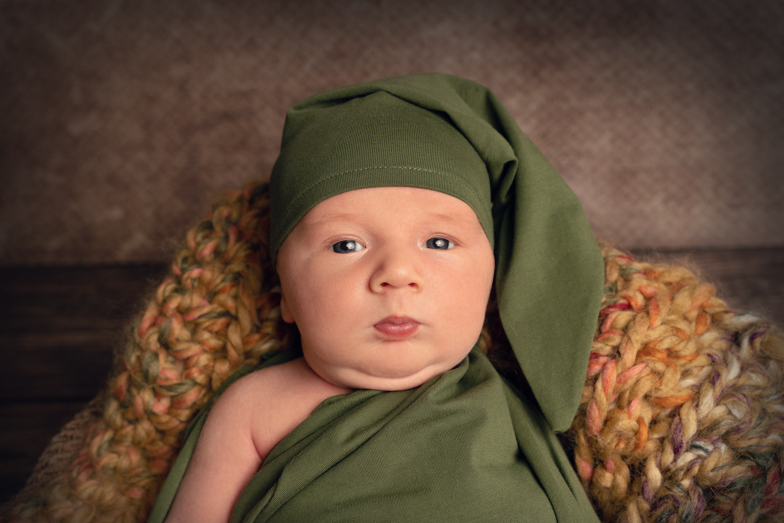 Ein Baby liegt im Koffer und schaut in die Kamera