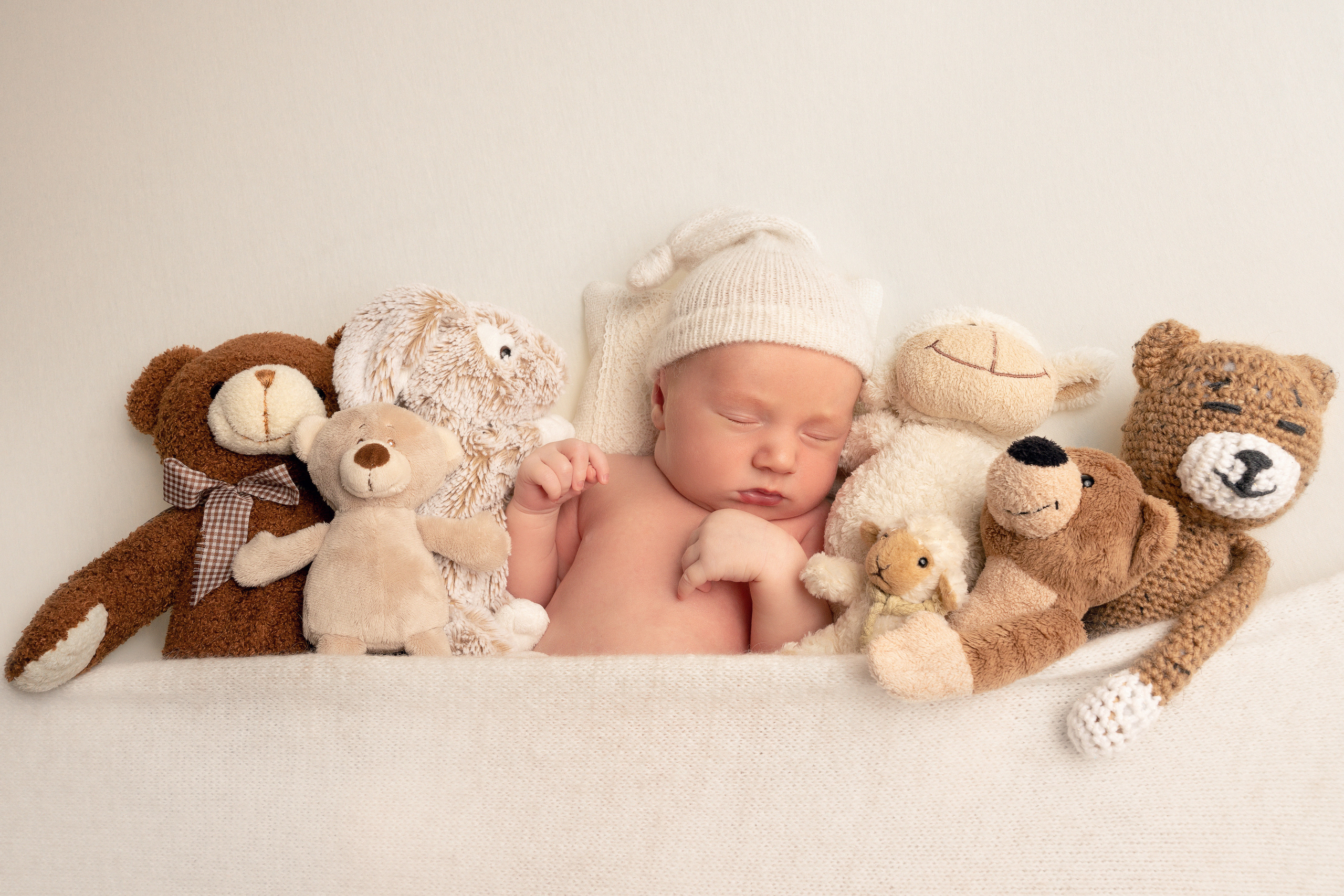 Ein kleiner Junge in einer Schale mit mehreren Plüschtieren