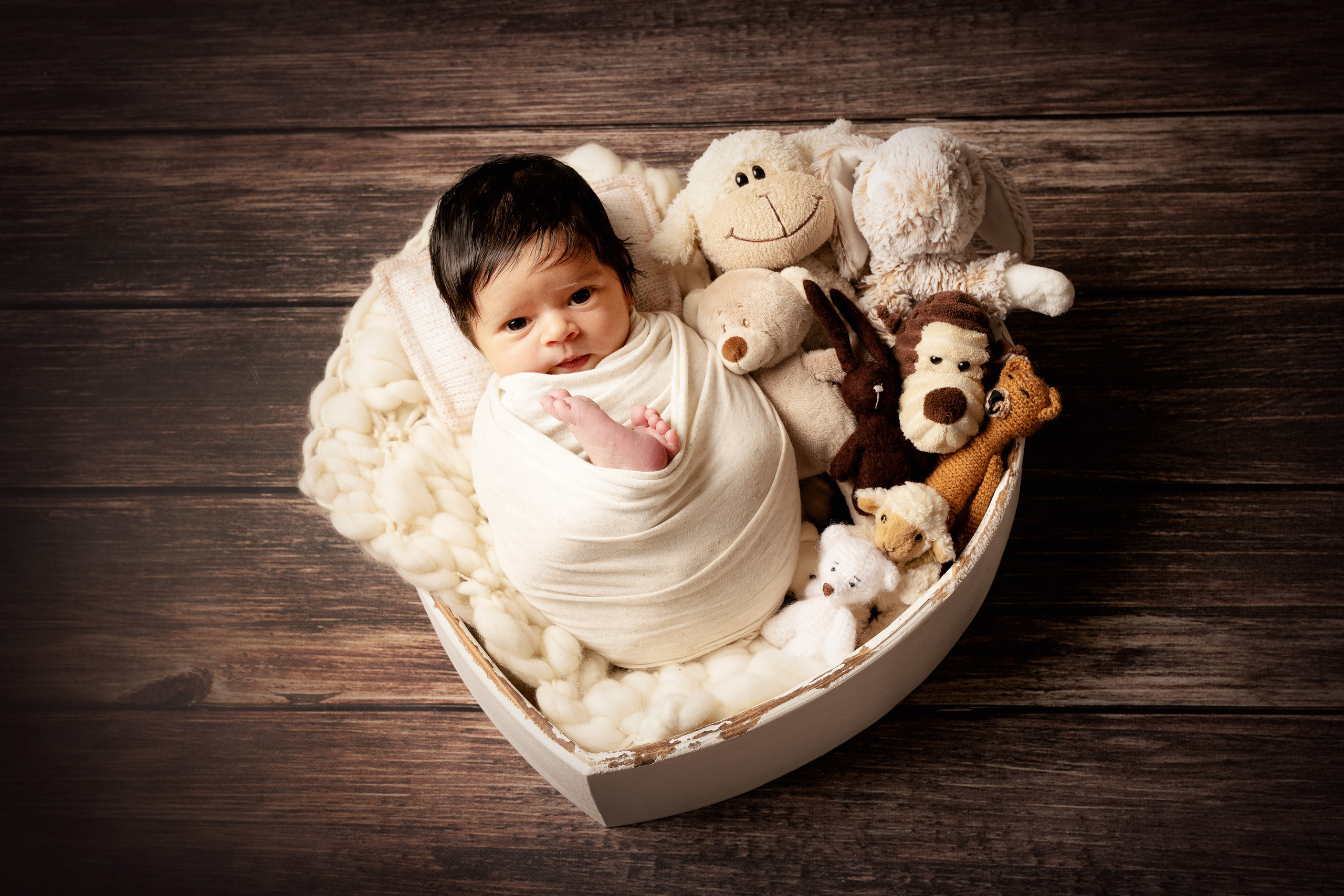 Ein kleines Mädchen posiert in einem Korb mit Blumen und Schmetterlingen