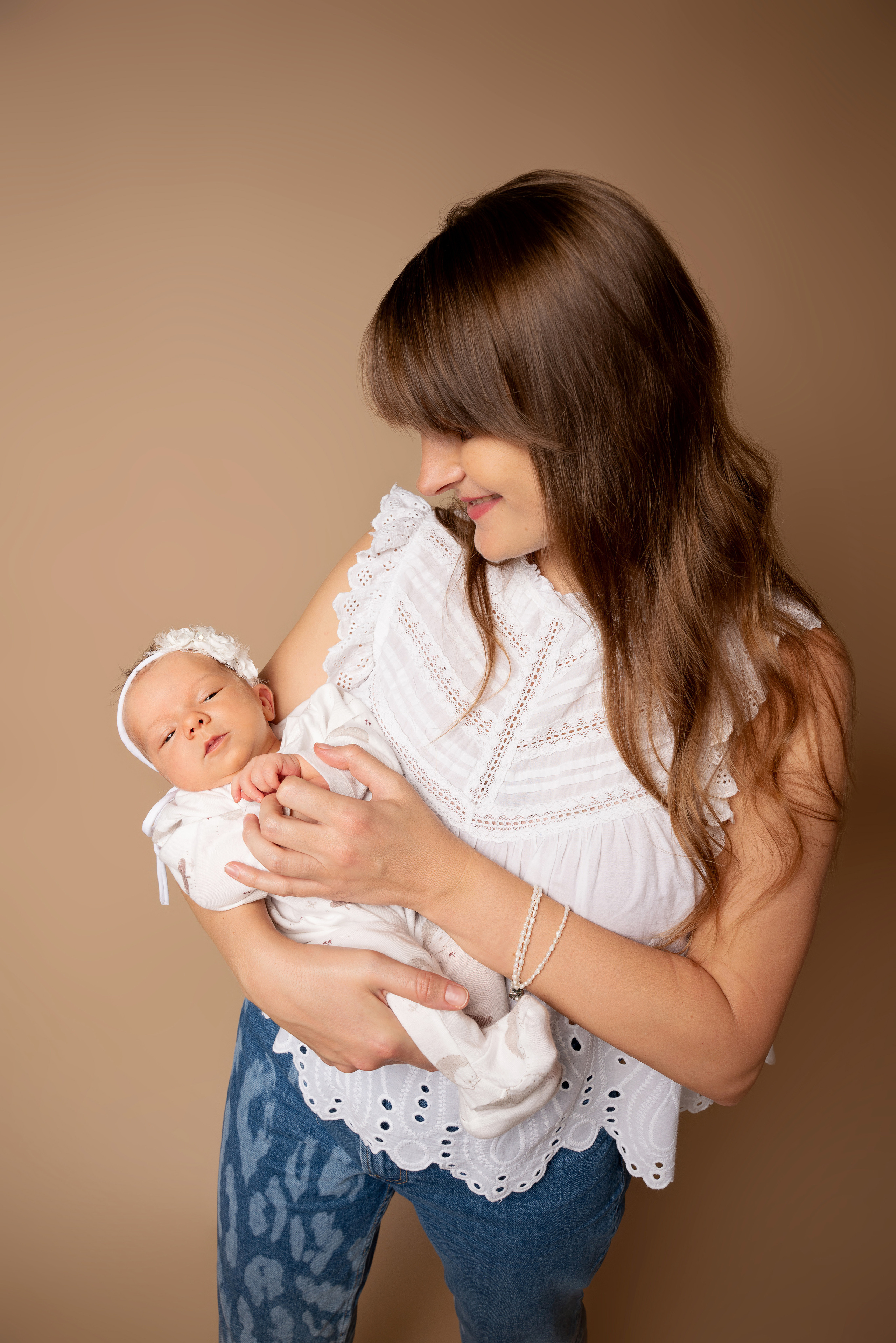 Eine Frau trägt ein hübsches Kleid und posiert stolz mit ihrem Baby