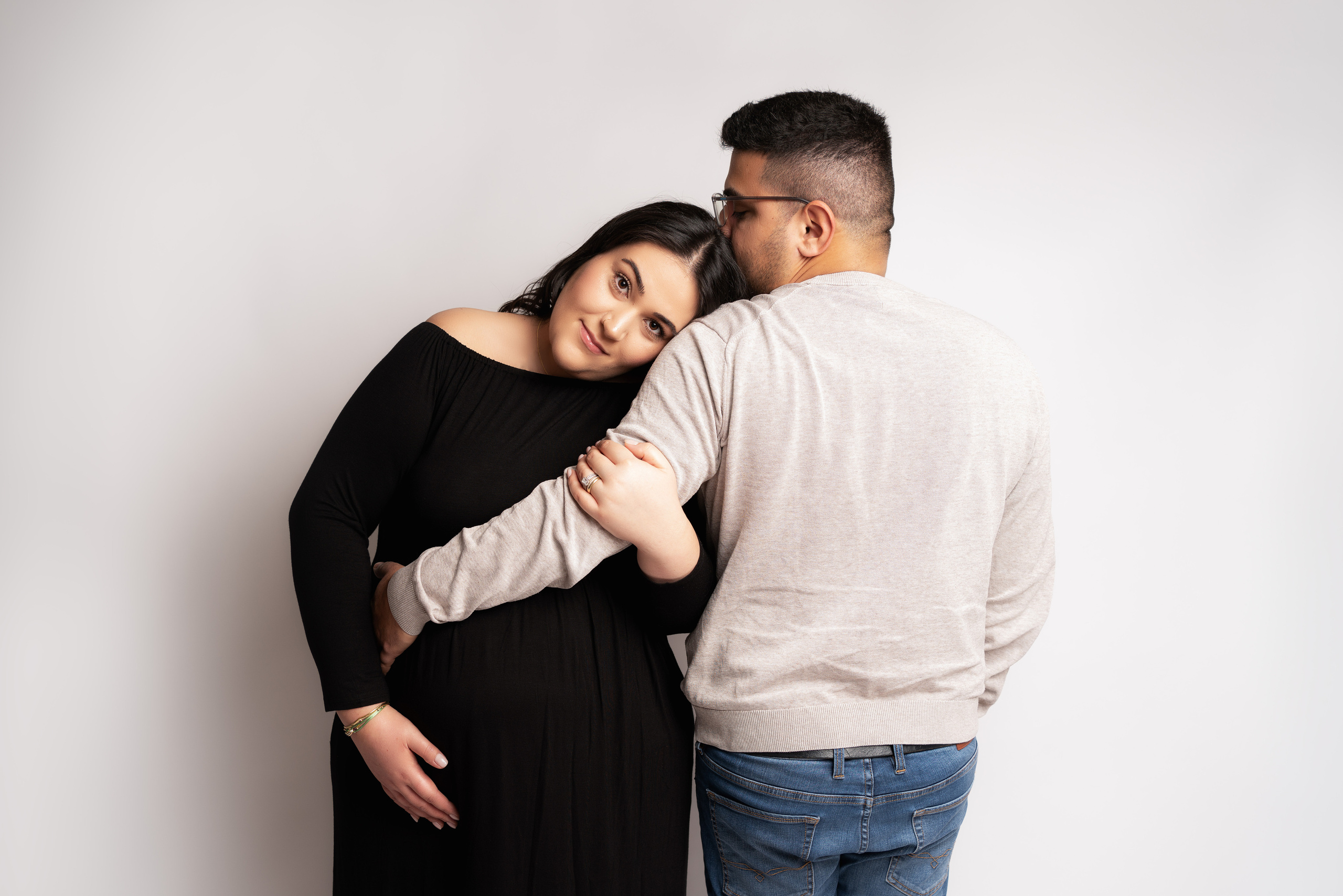 Ein Paar posiert am Strand mit einem Schild, auf dem "Wir werden Eltern" steht