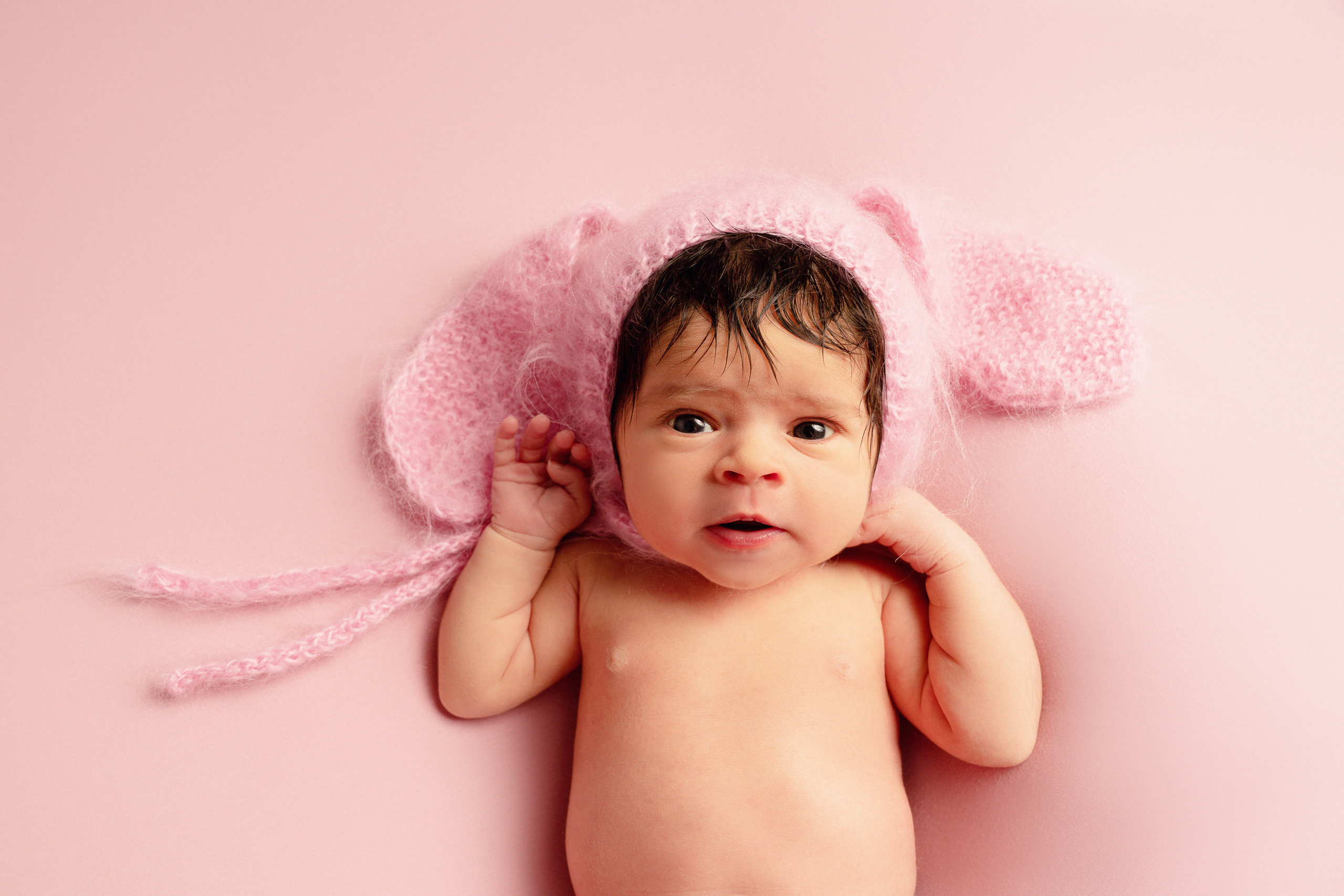 Baby in einem rosa Hut mit Hasenohren