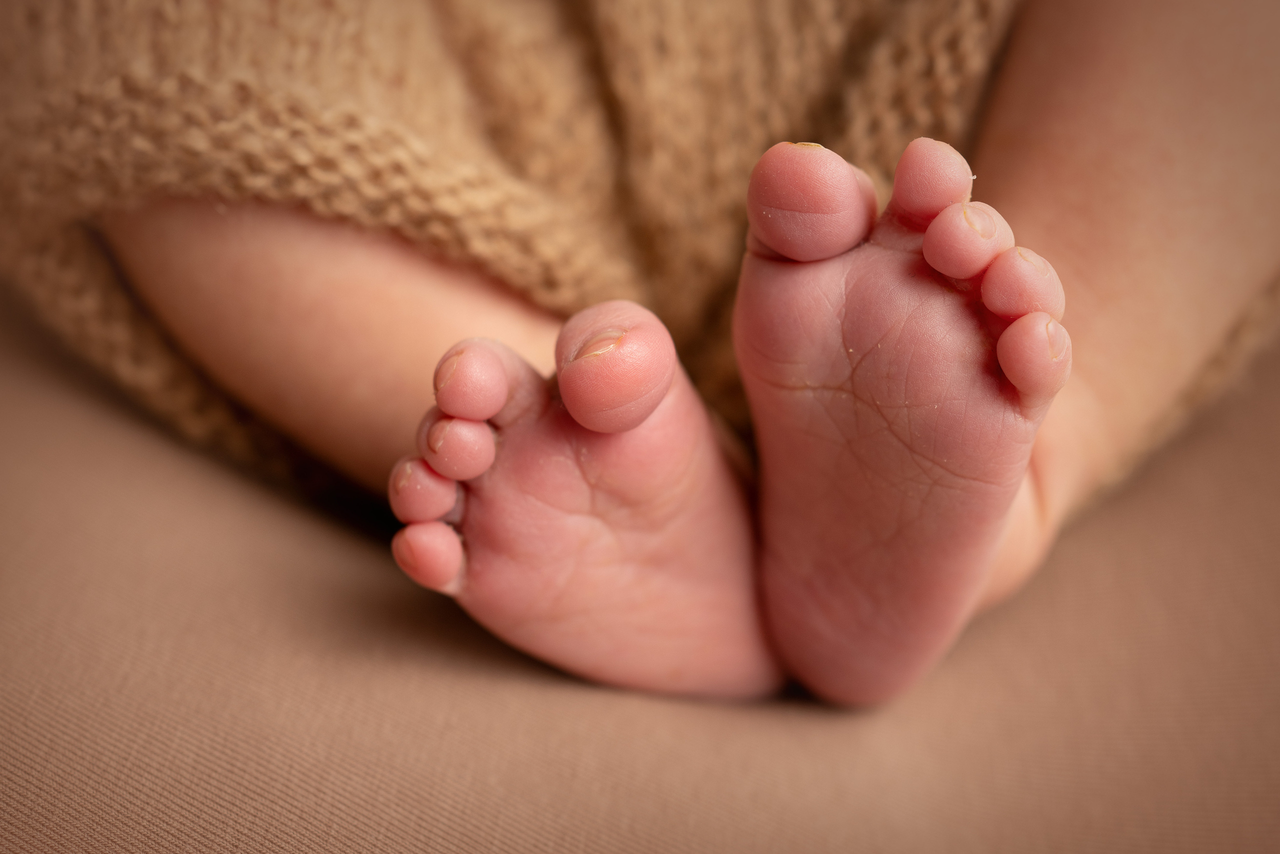 Zwei kleine Füße, die auf den Händen eines Erwachsenen ruhen