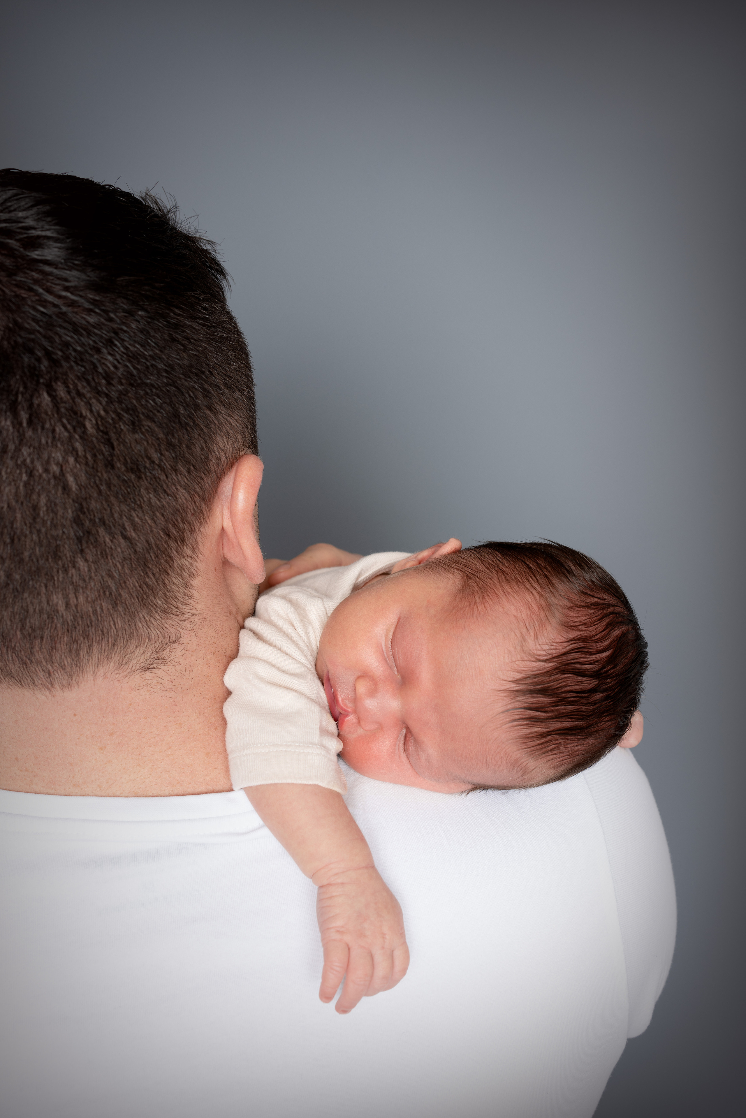 Baby schläft auf Papas Schulter und lässt seinen Arm baumeln