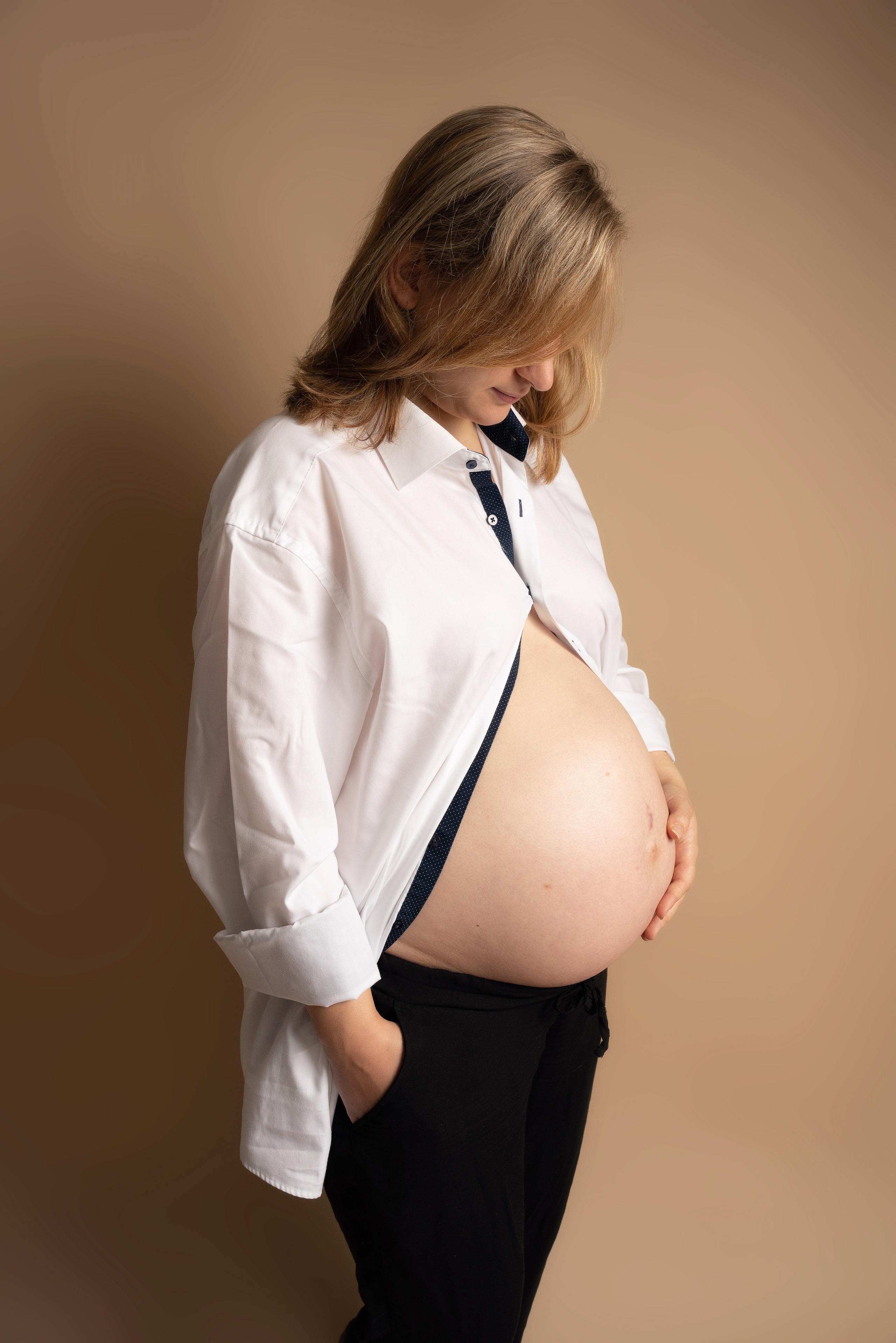Eine Frau mit babybauch posiert in einem PhotoStudio