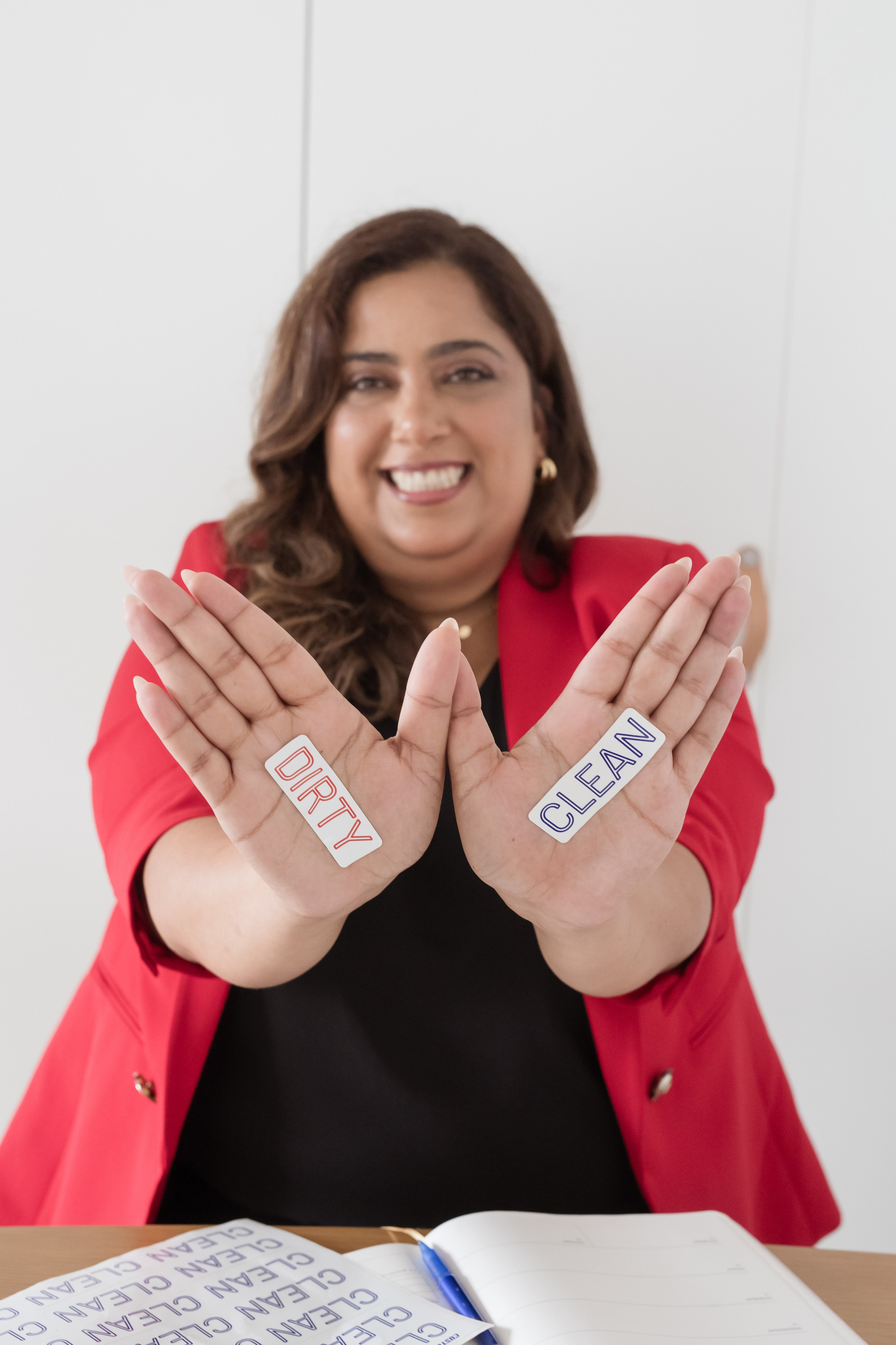 women in red blazer holds her hands up with words "clean" and "dirty"