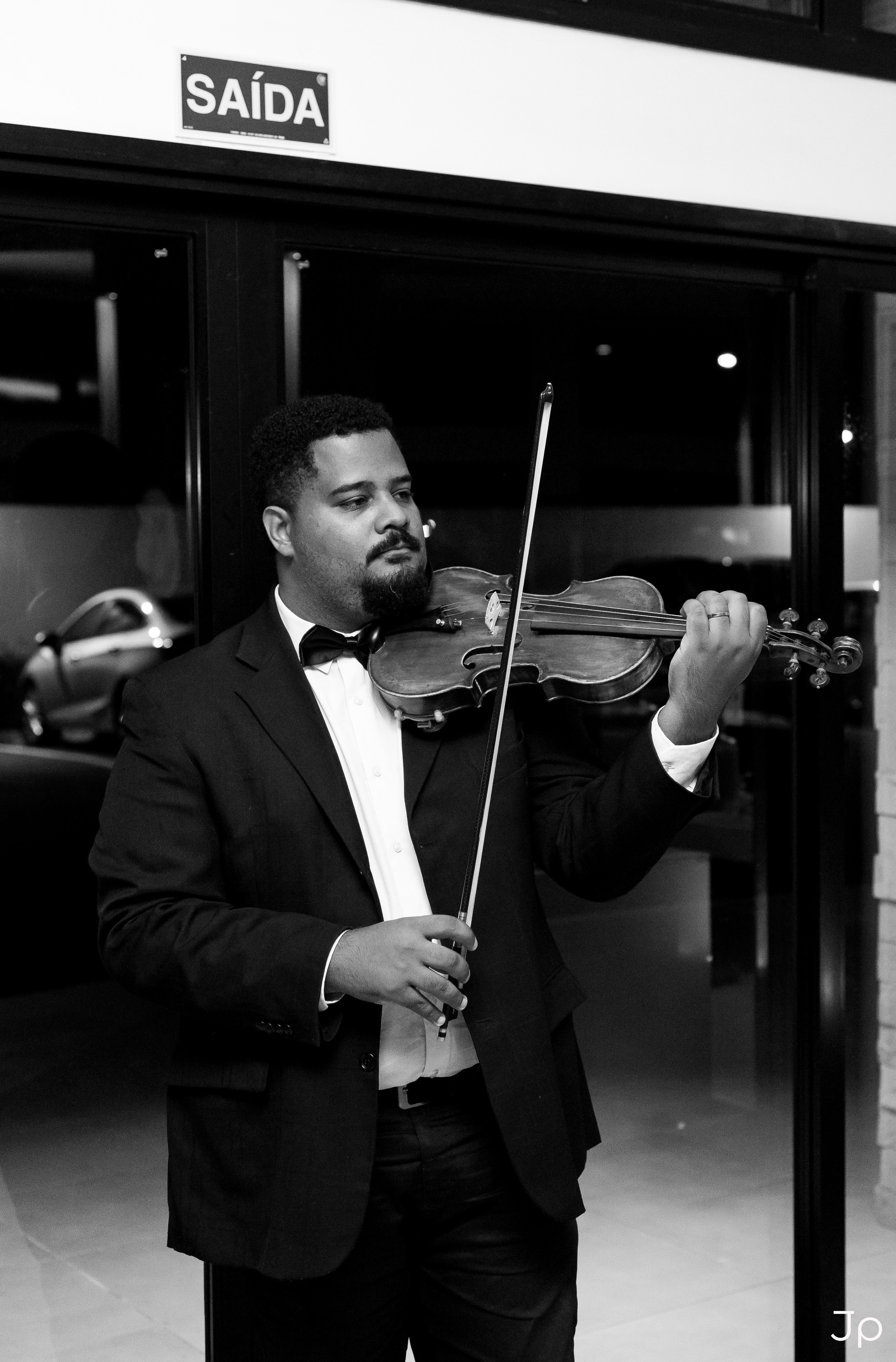 Músico de terno tocando violino na entrada do salão em Agudos