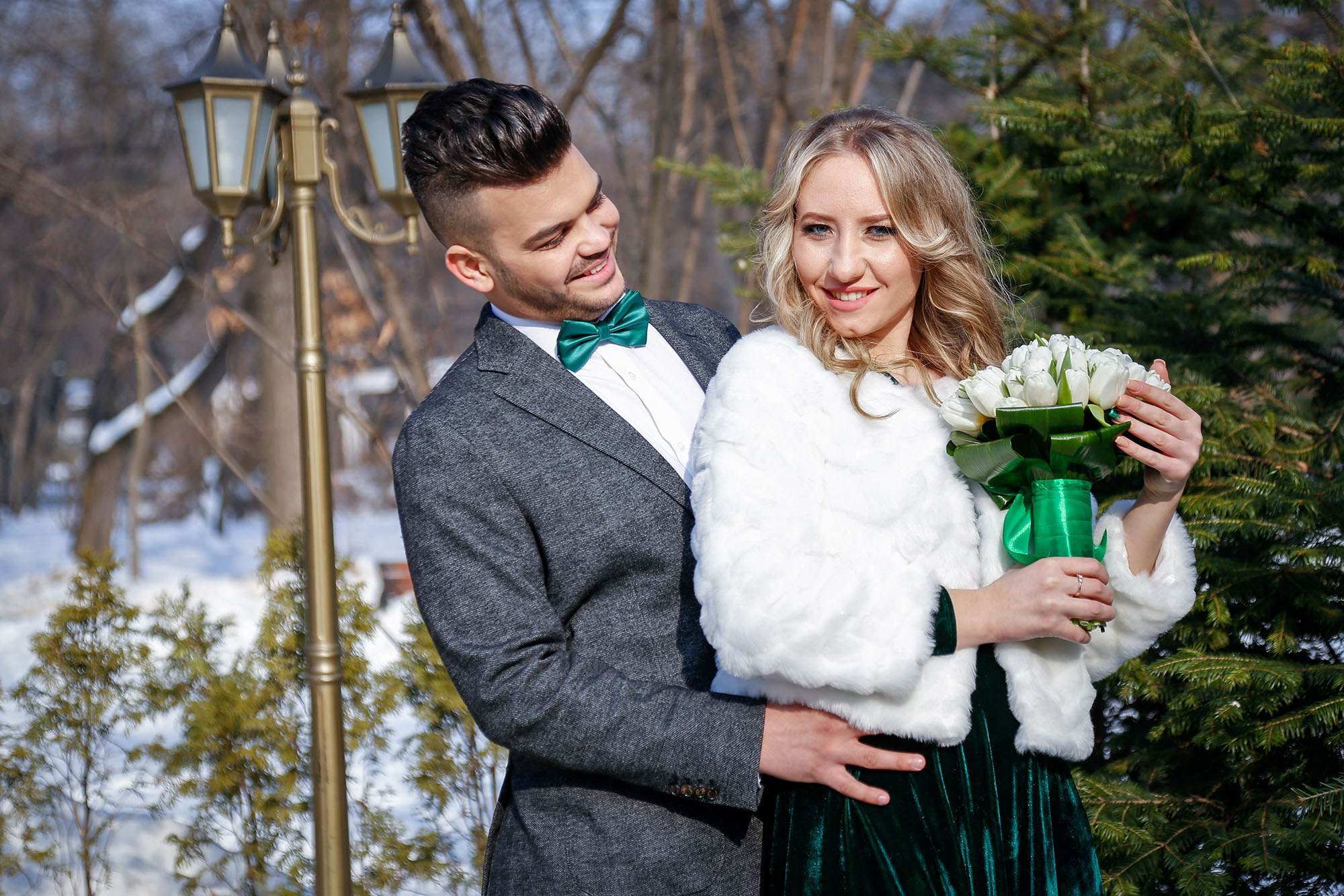 Smiling newlyweds standing close together, photographed outdoors, highlighting their joy and the snowflakes in the background.