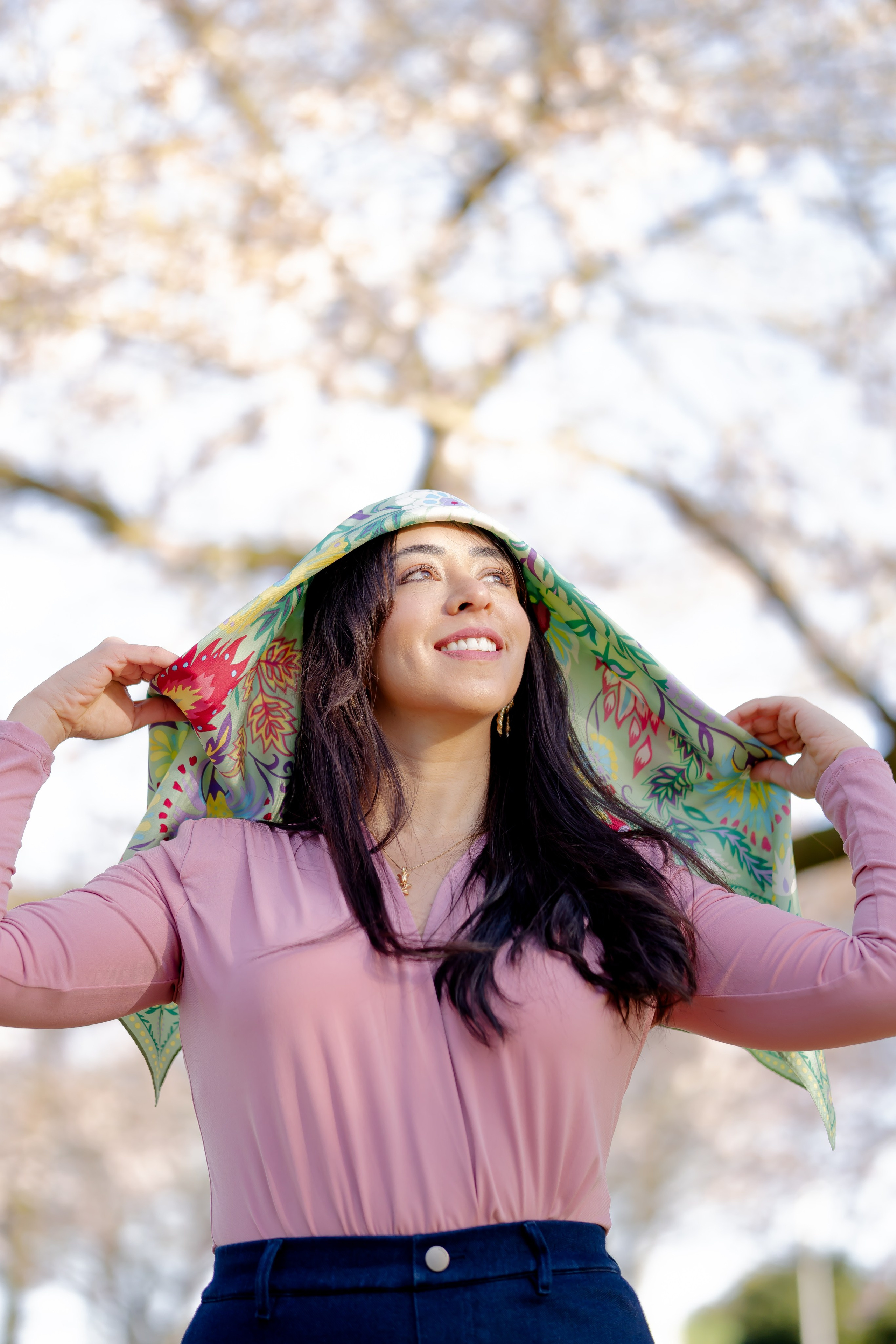 girl holding a scarf on her head and enjoying the cherry blossoms in Amsterdam