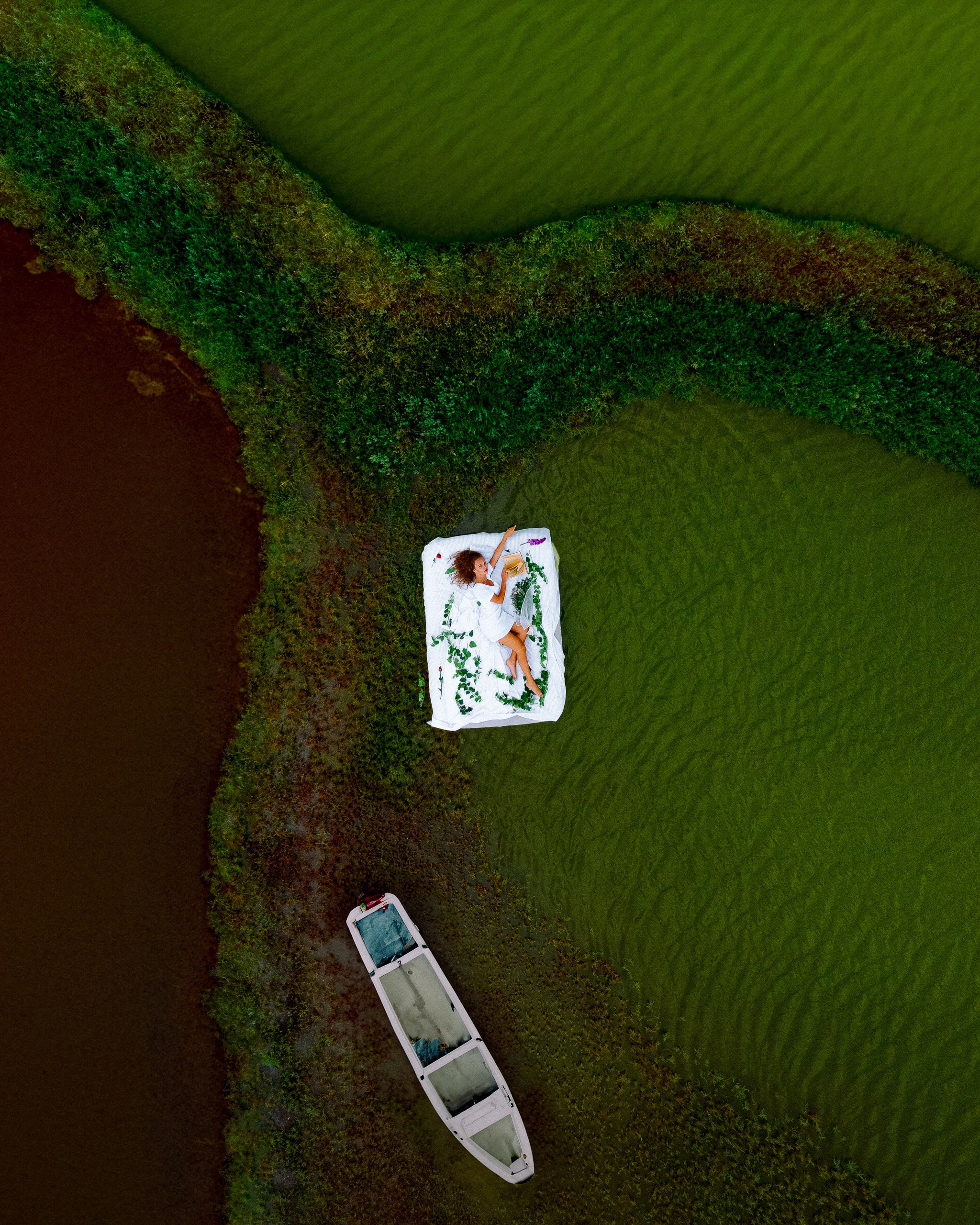 A photo from a drone of a girl on a mattress in a lake 