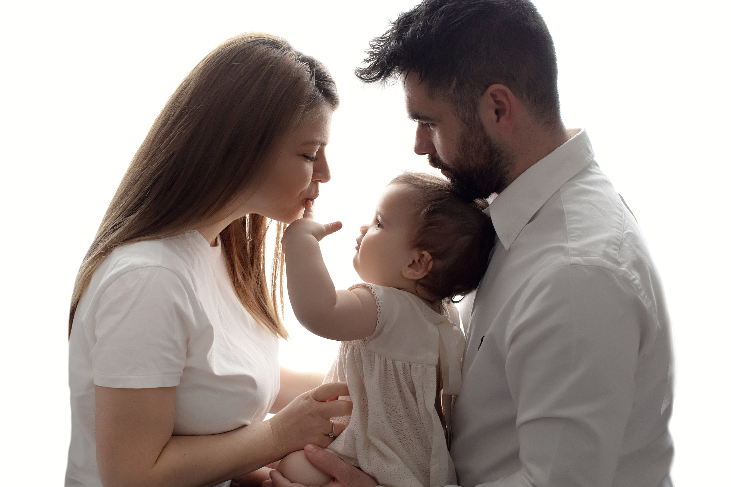 Familjefotografering i studion fångar ögonblicket av lycka med barn, mamma och pappa tillsammans.