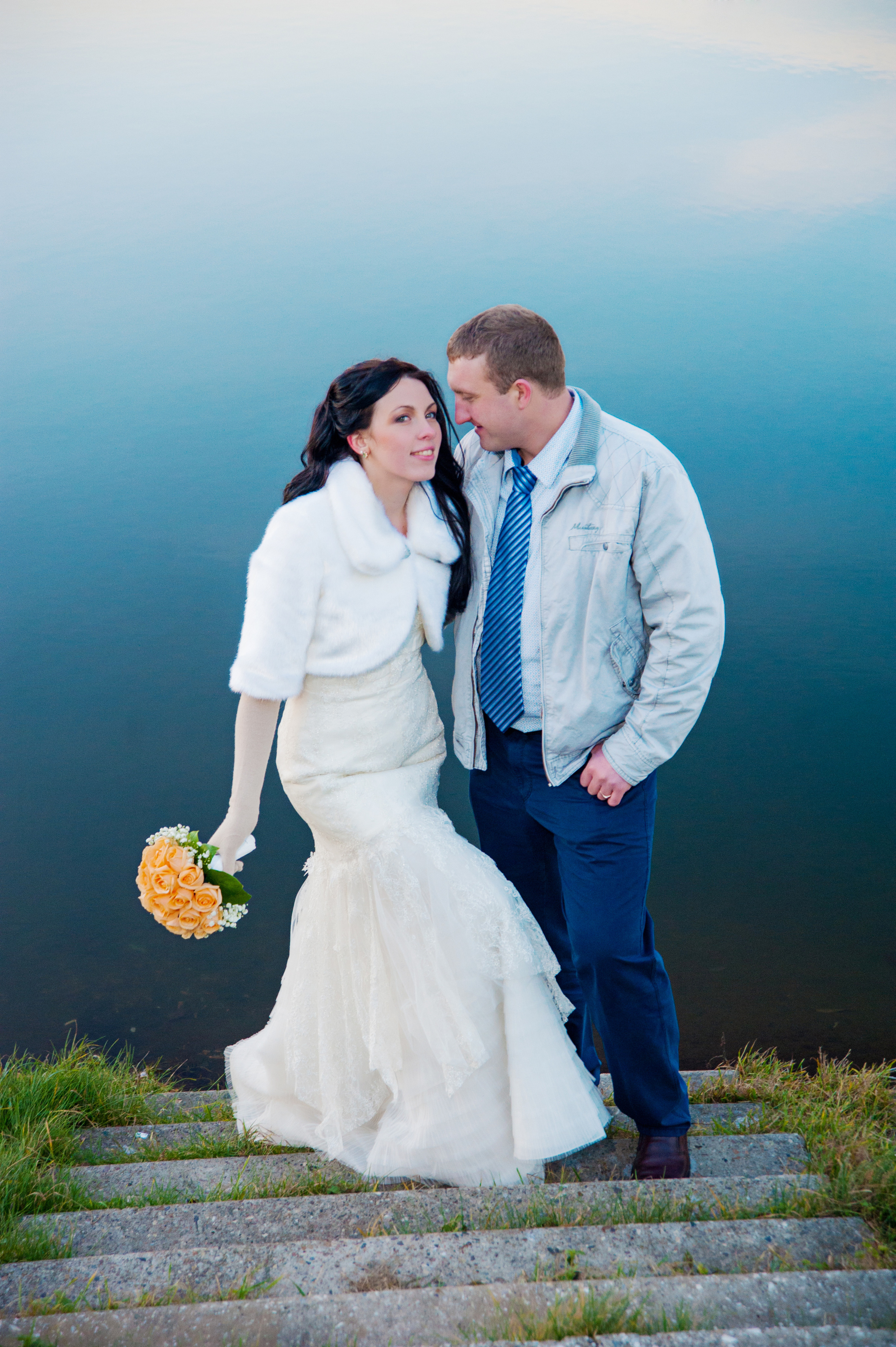 Свадебная фотосессия в Москве. Молодожены стоят на бетонной лестнице у воды у озера