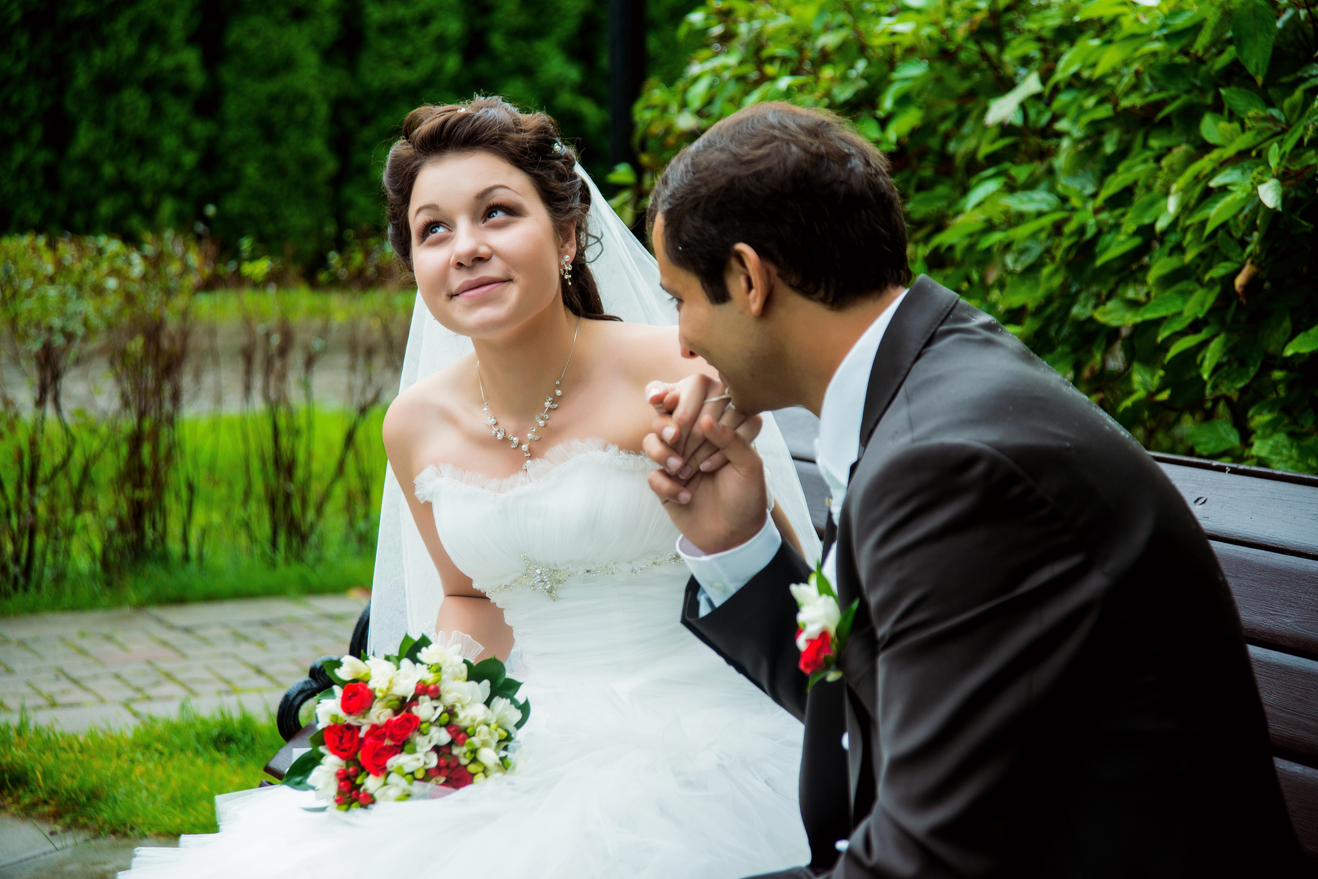 Свадебная фотосессия в Москве. Жених целует руку невесты на скамейке в парке на Рублевке
