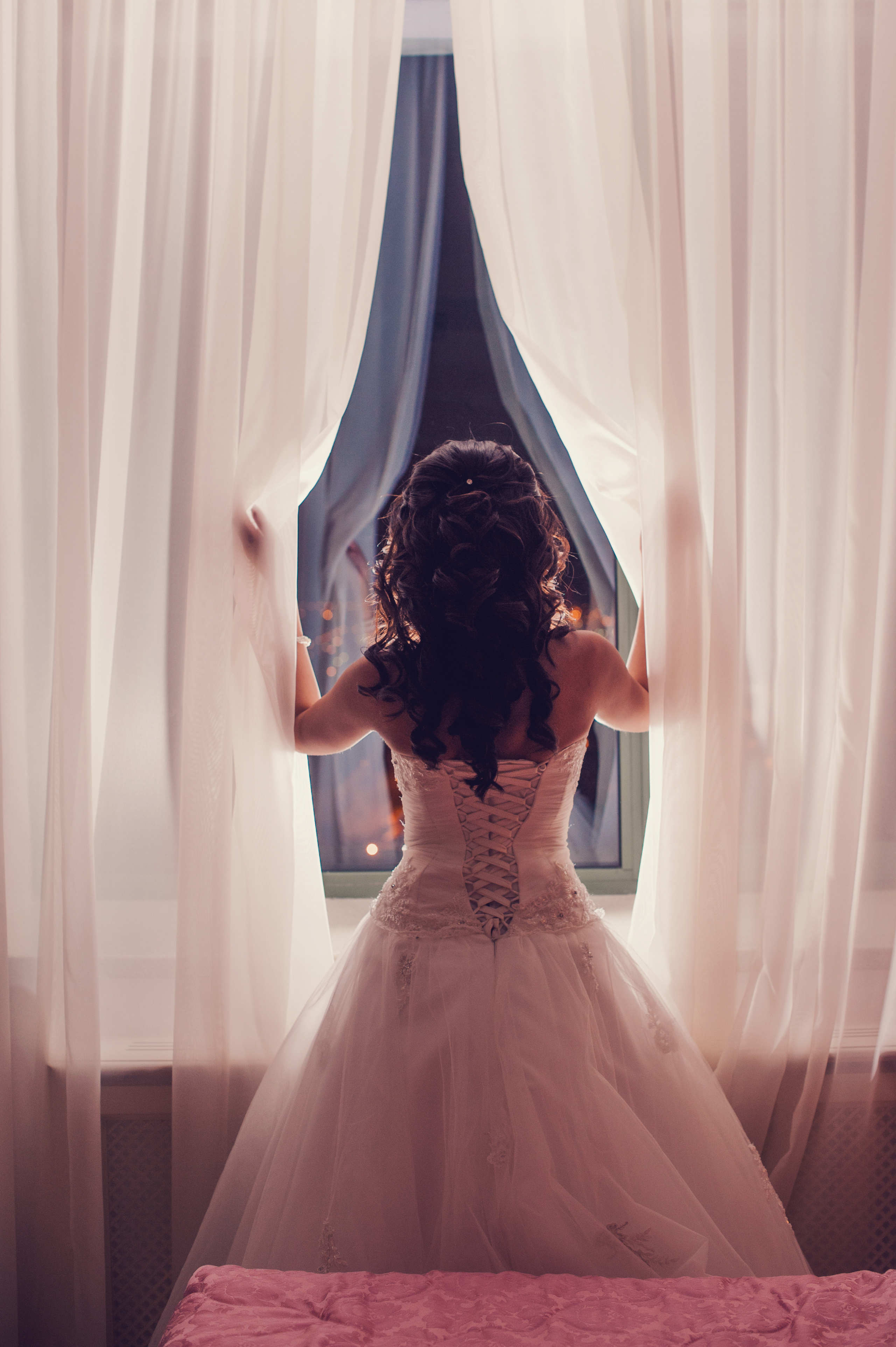 Свадебная фотосессия в Москве. Сборы невесты в отеле Милан. Невеста стоит у окна раздвигая шторы руками