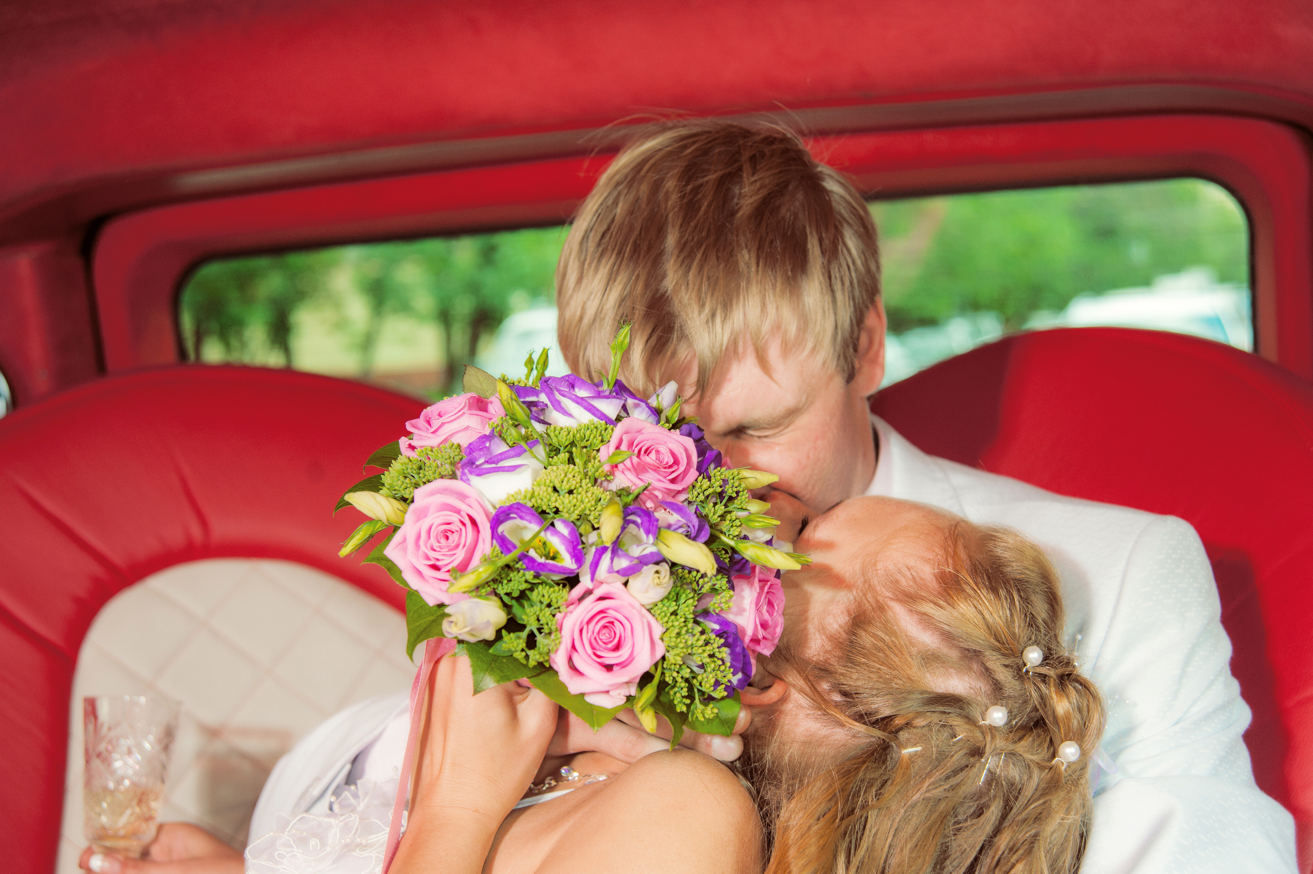 Свадебная фотосессия в Москве. Жених и невеста целуются в свадебном лимузине, прячутся за букетом невесты.