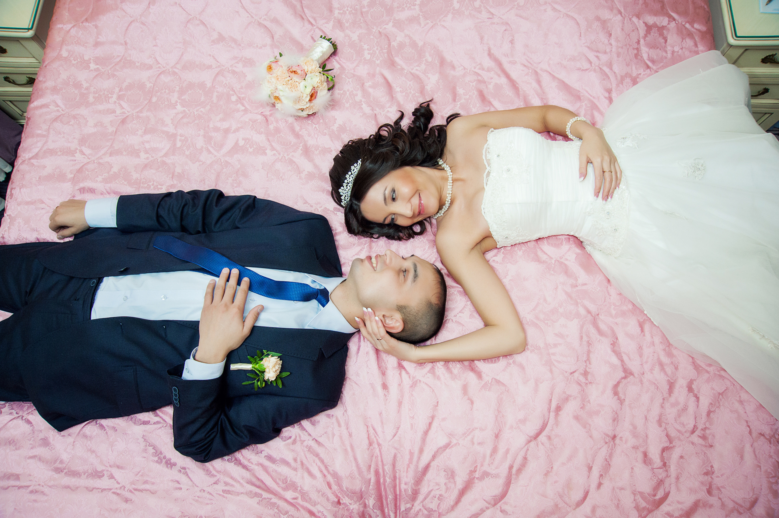 Свадебная фотосессия в Москве. Жених и невеста лежат на кровати на розовом покрывале