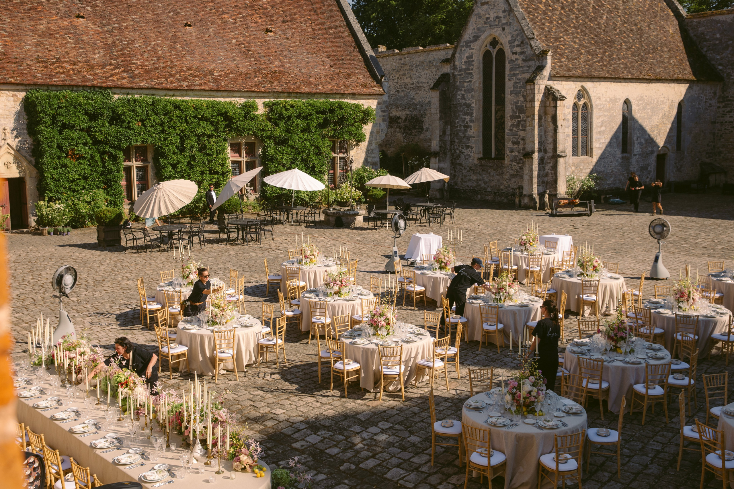 Outdoor wedding dinner setup with long table in French château courtyard