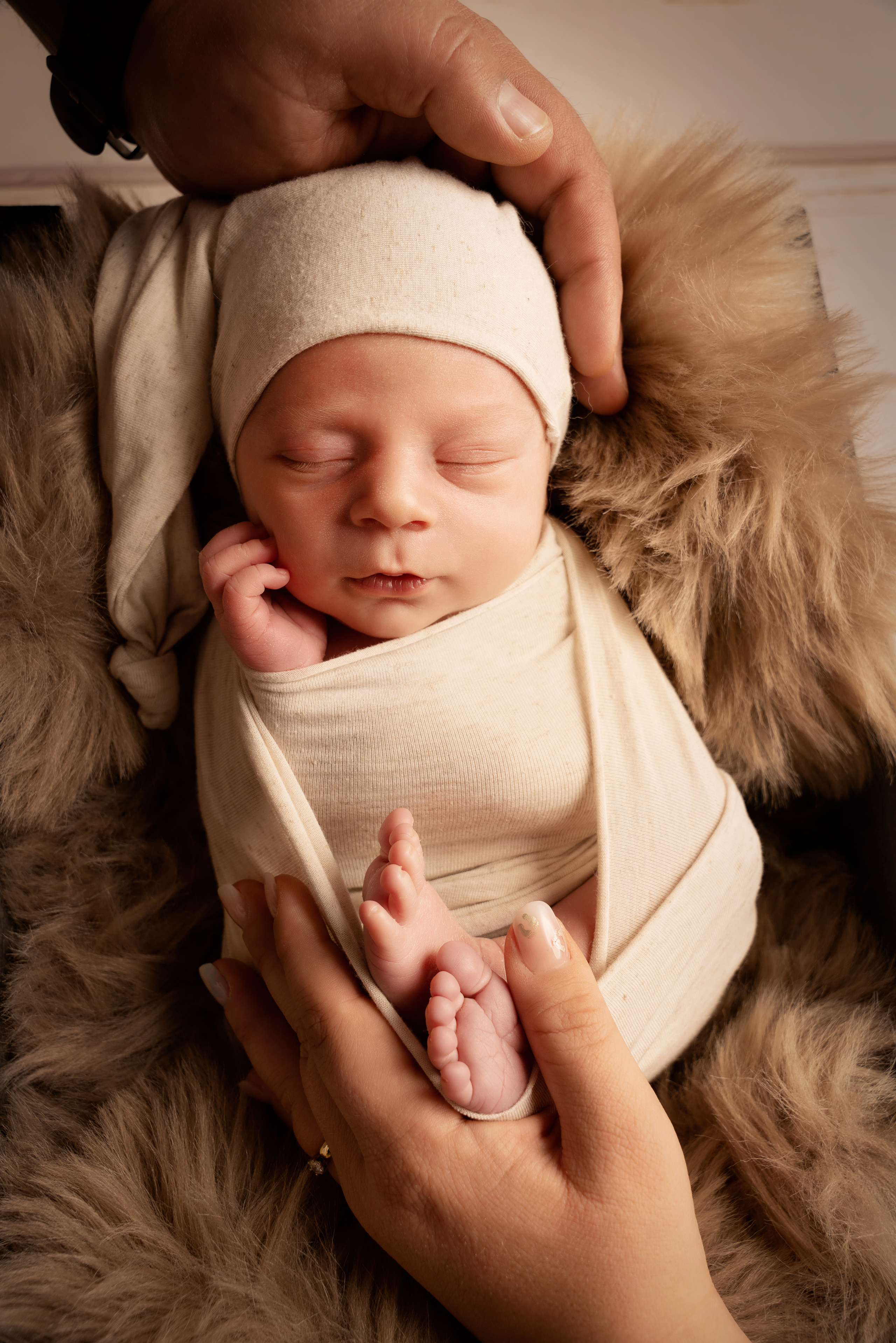 schlafendes Neugeborenes in dem  blauen Korb und die Hände seiner Eltern