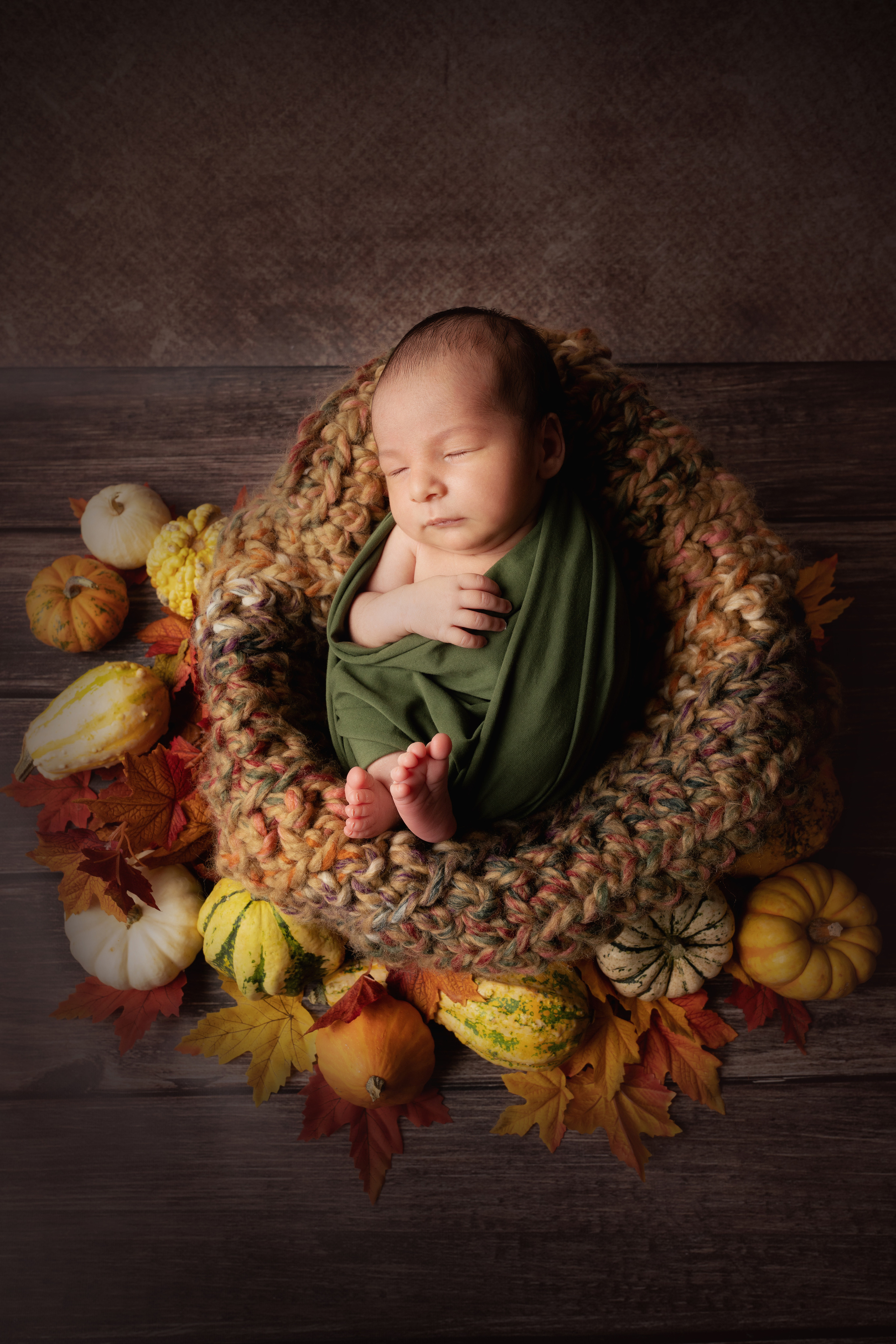 Baby schläft zwischen orangefarbenen und gelben kleinen Kürbissen