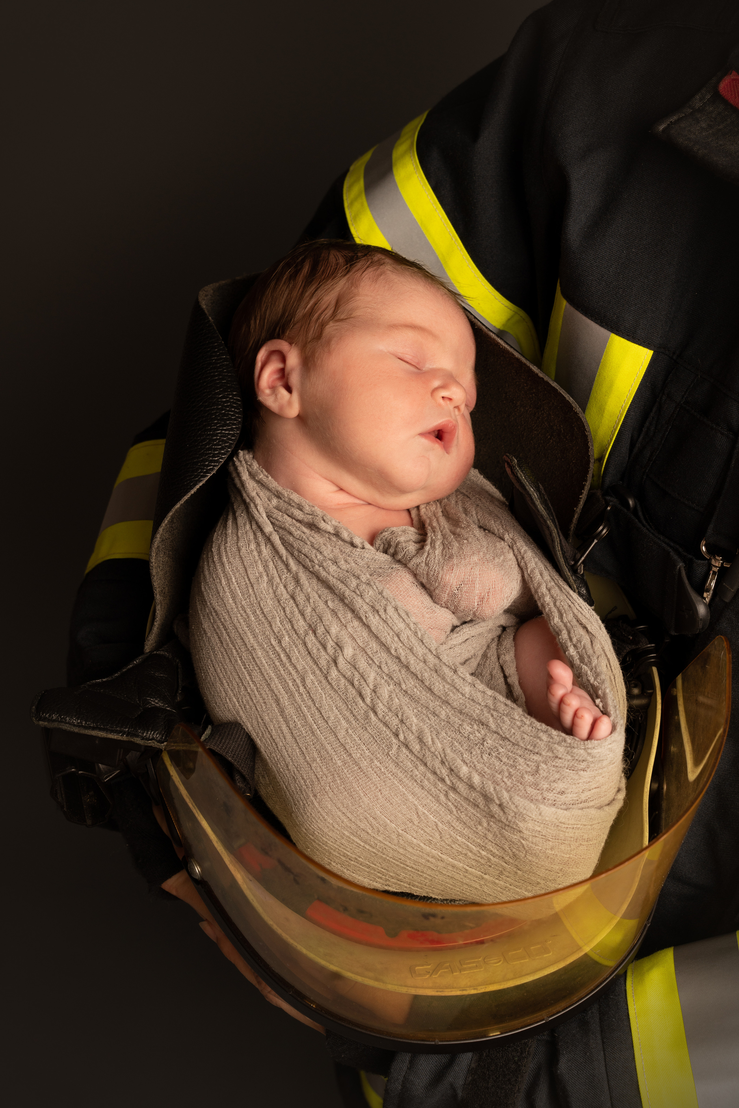 Neugeborene Tochter eines Feuerwehrmannes schläft in einem Feuerwehrhelm