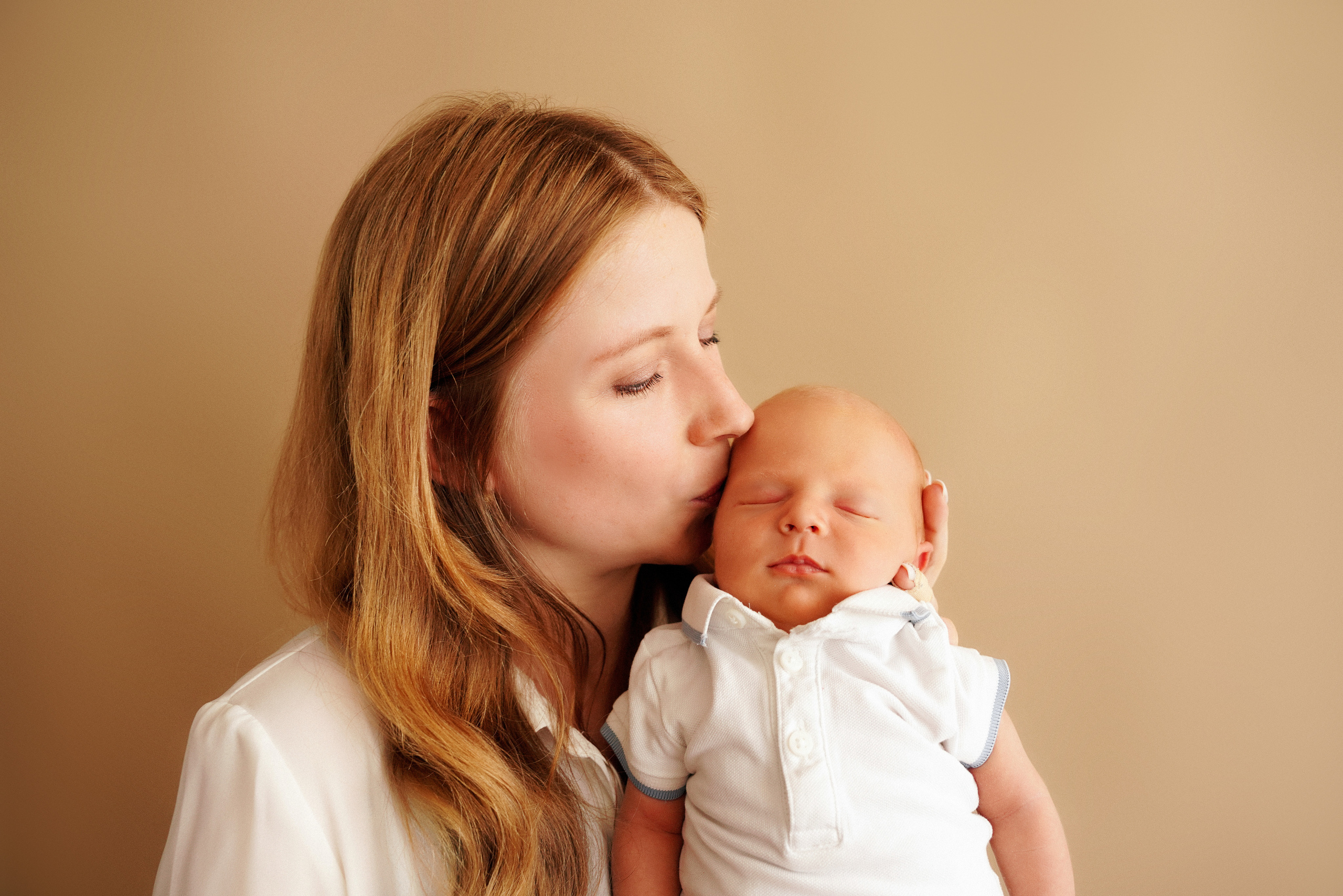 Porträt einer Mutter mit einem Kind auf einem weizenfarbenen Hintergrund