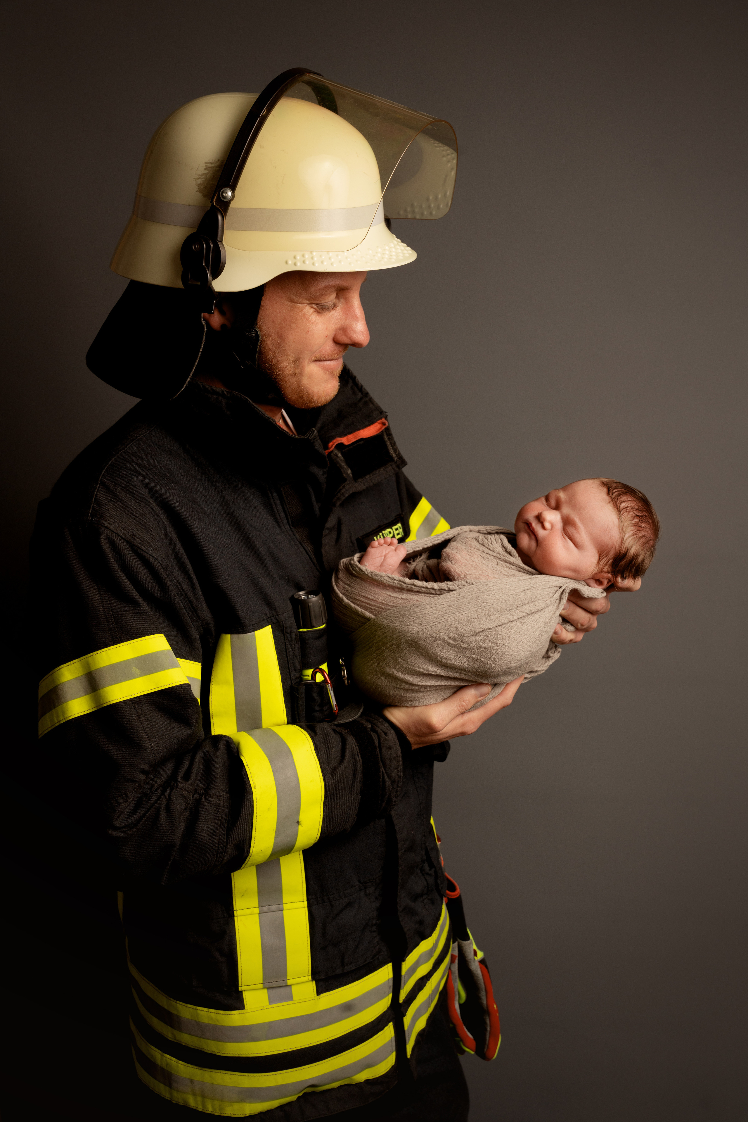 Papa Feuerwehrmann in einem Rettungsanzug mit einer neugeborenen Tochter
